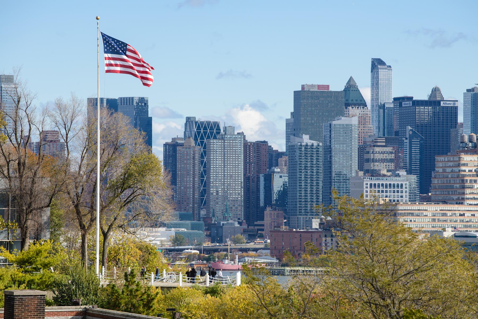 American flag flys on Stevens campus at Castle Point with New York city in background.
