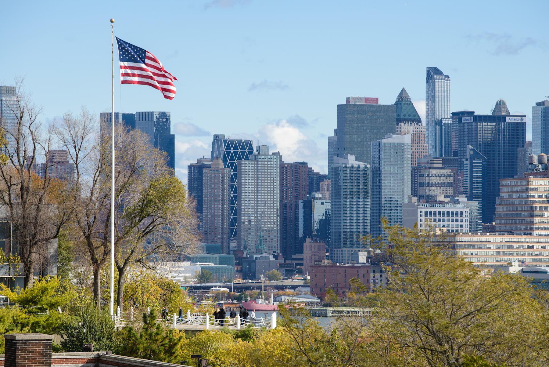 American flag flys on Stevens campus at Castle Point with New York city in background.