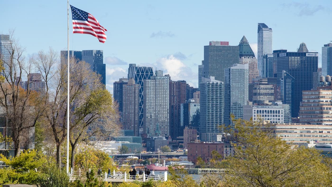 American flag flys on Stevens campus at Castle Point with New York city in background.