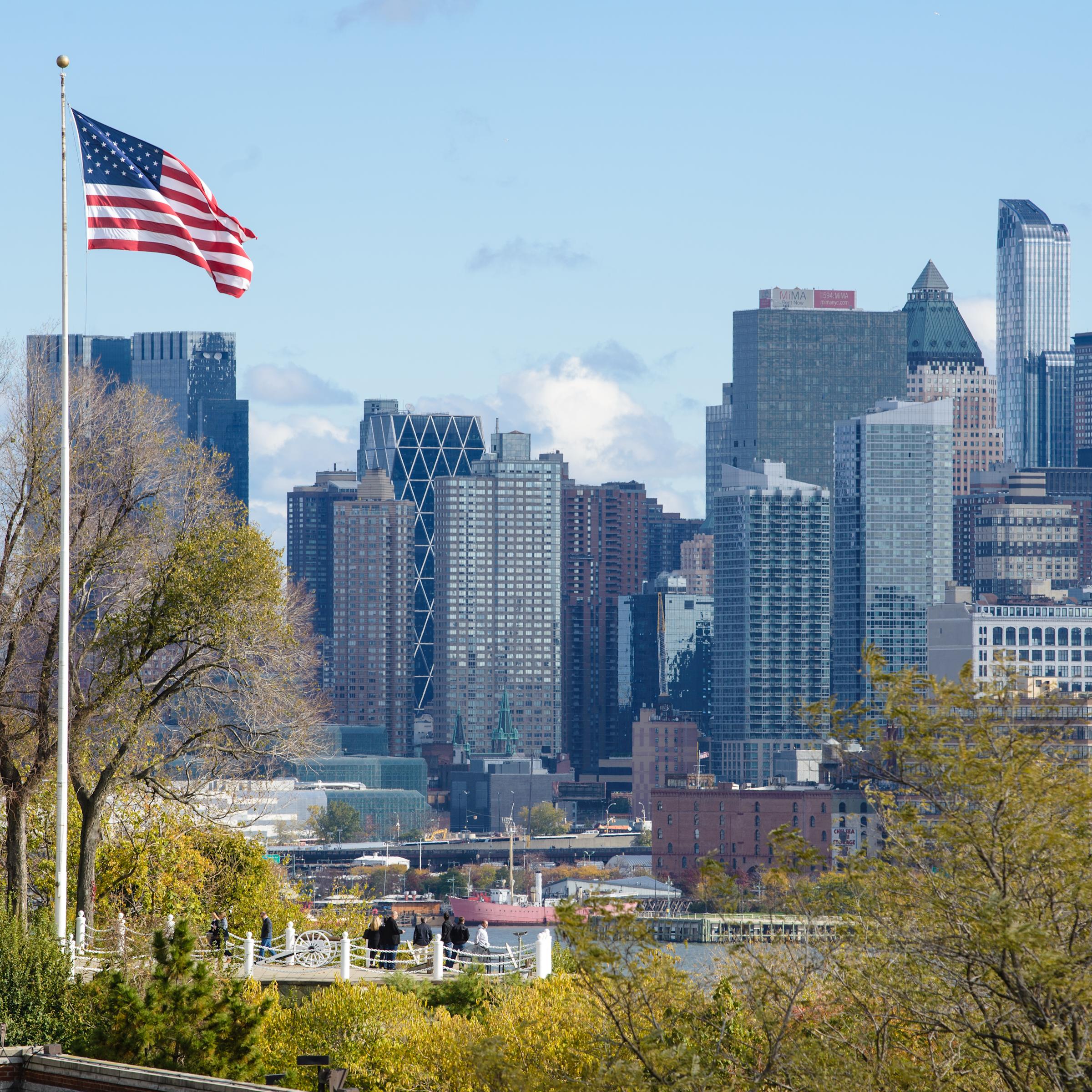American flag flys on Stevens campus at Castle Point with New York city in background.