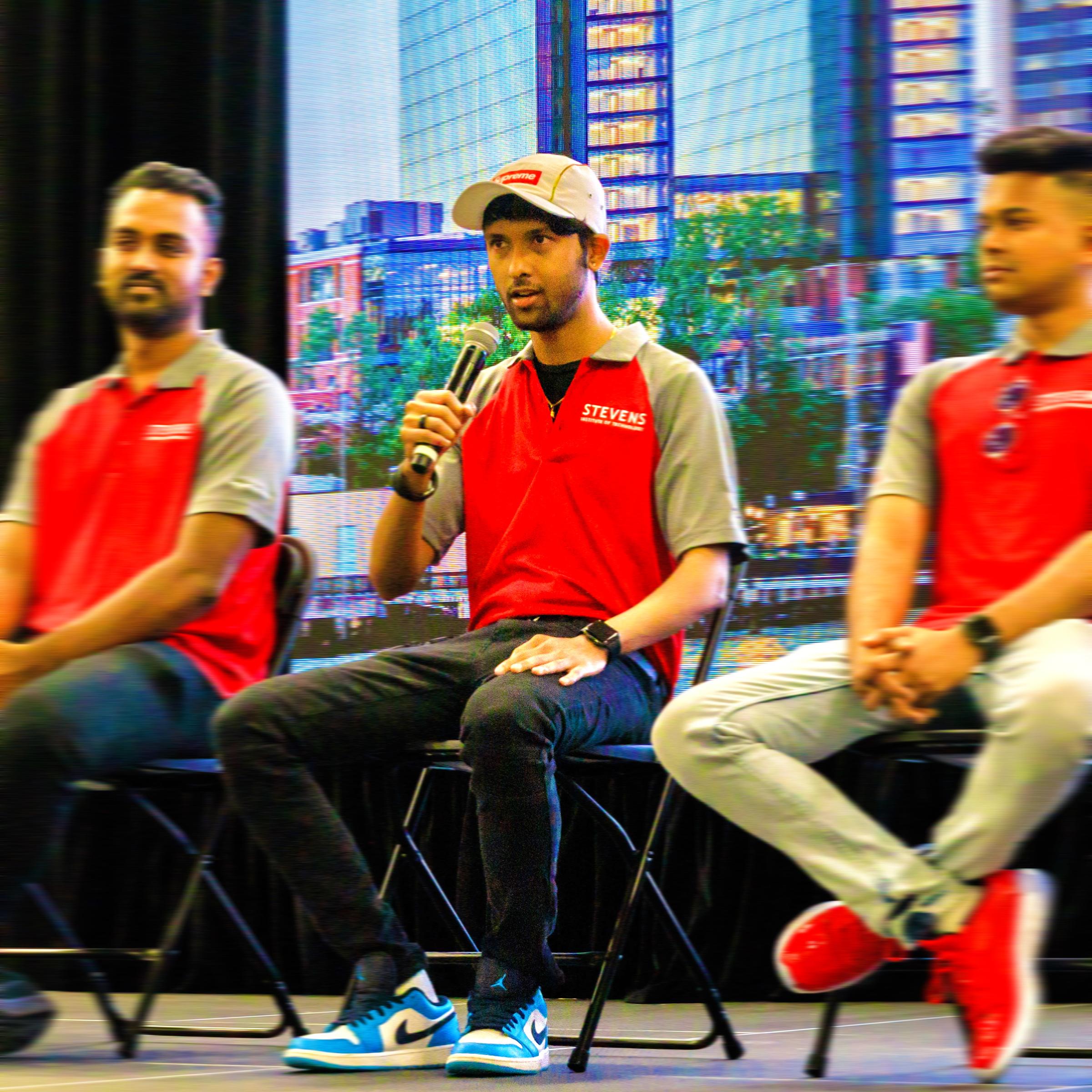 Shardule Shinde holds a microphone and speaks to an audience during a networking event.