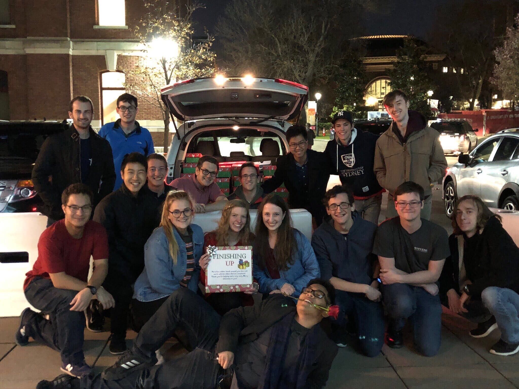 Group of students in front of a car with presents in the trunk