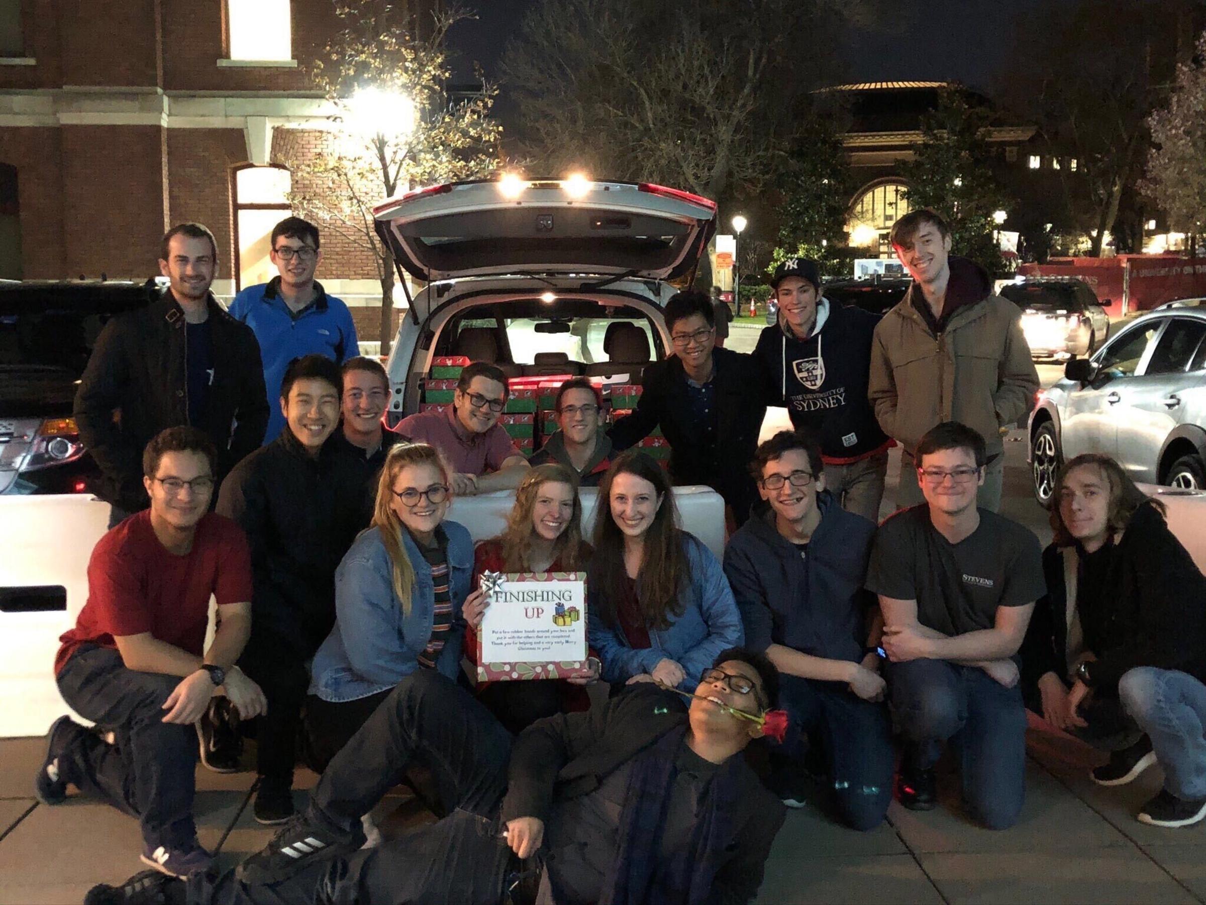 Group of students in front of a car with presents in the trunk
