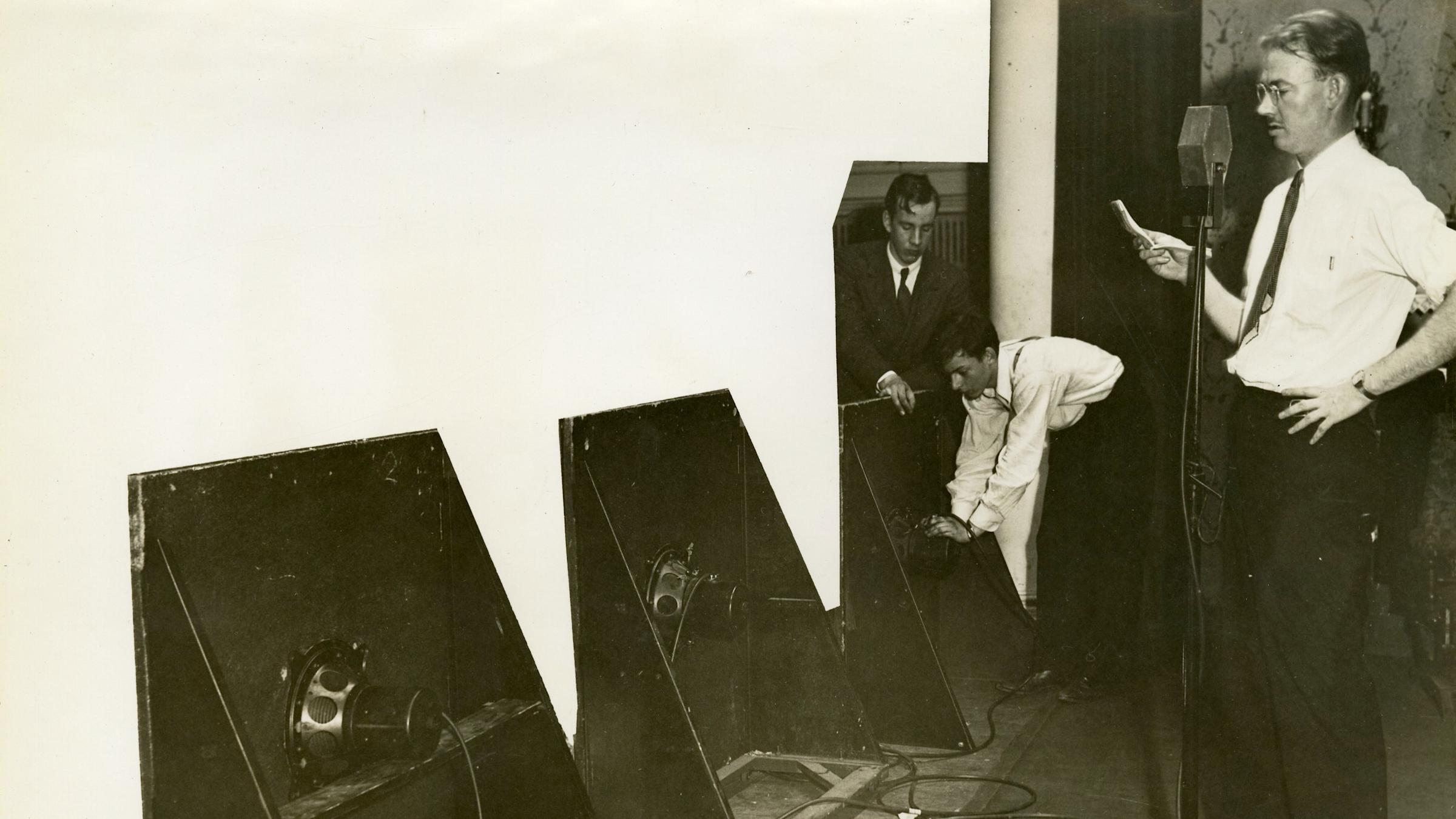 Burris-Meyer in front of a microphone with speakers staged to demonstrate progressive sound.