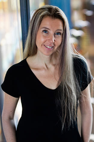 Milla Wirén stands before a window with a city street in the background.