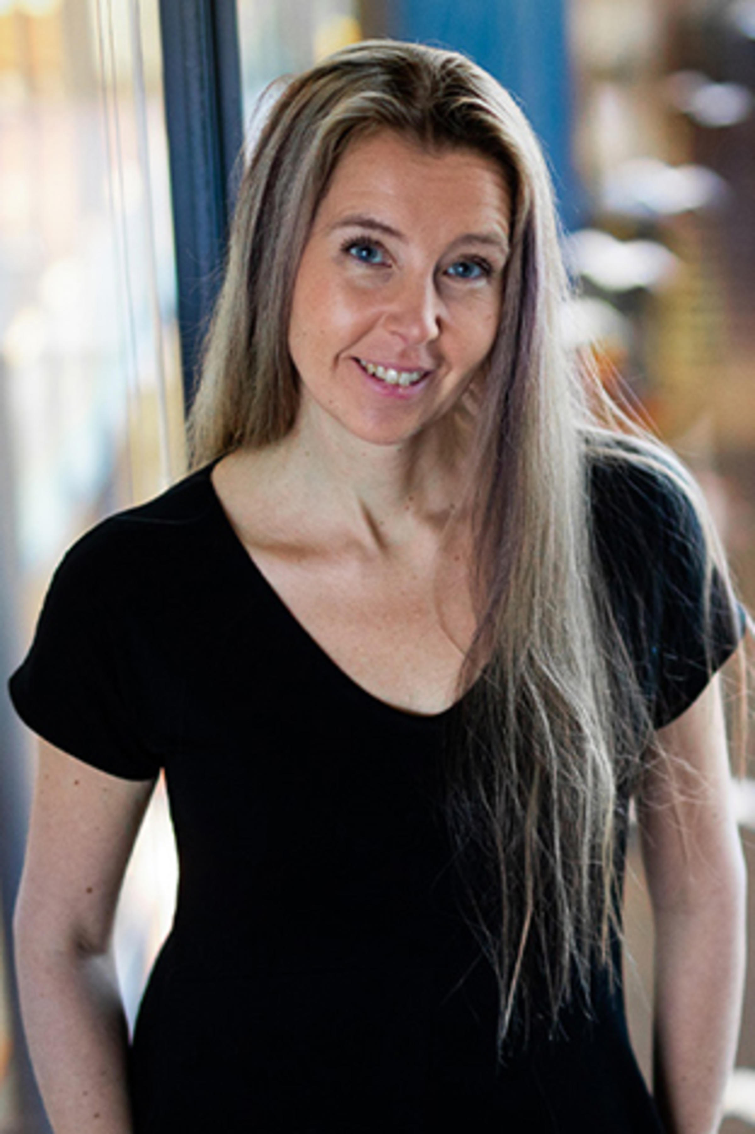 Milla Wirén stands before a window with a city street in the background.