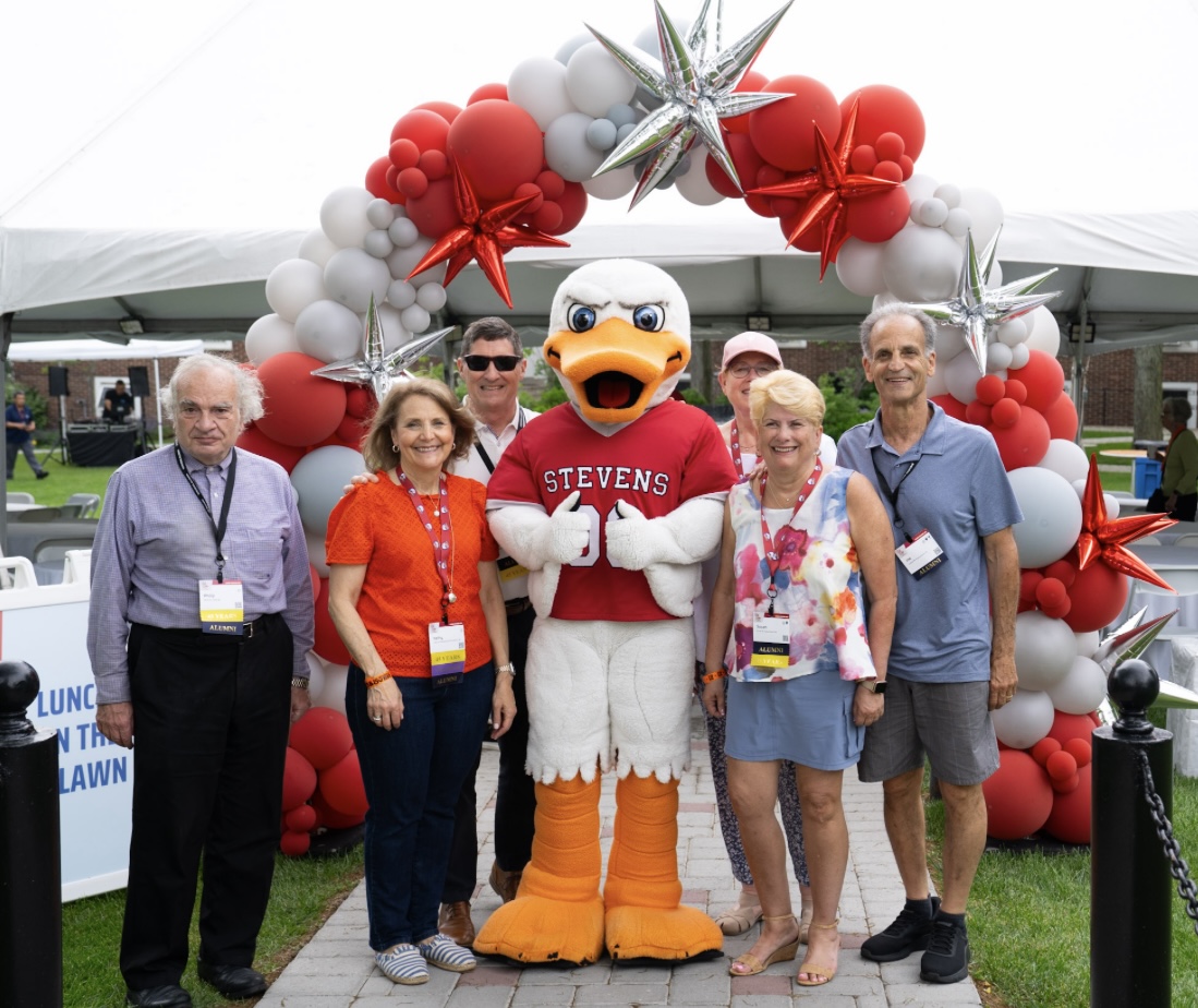 Alumni pose with Attila at the balloon arch during Alumni Weekend 2025