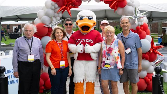 Alumni pose with Attila at the balloon arch during Alumni Weekend 2025