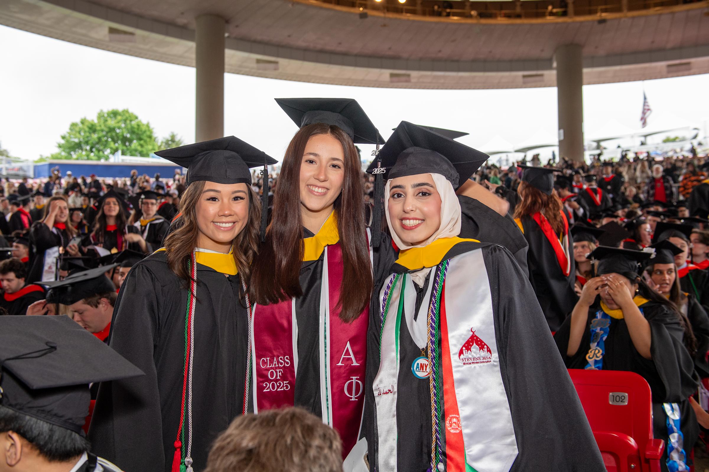 Three female students pose at Commencement.