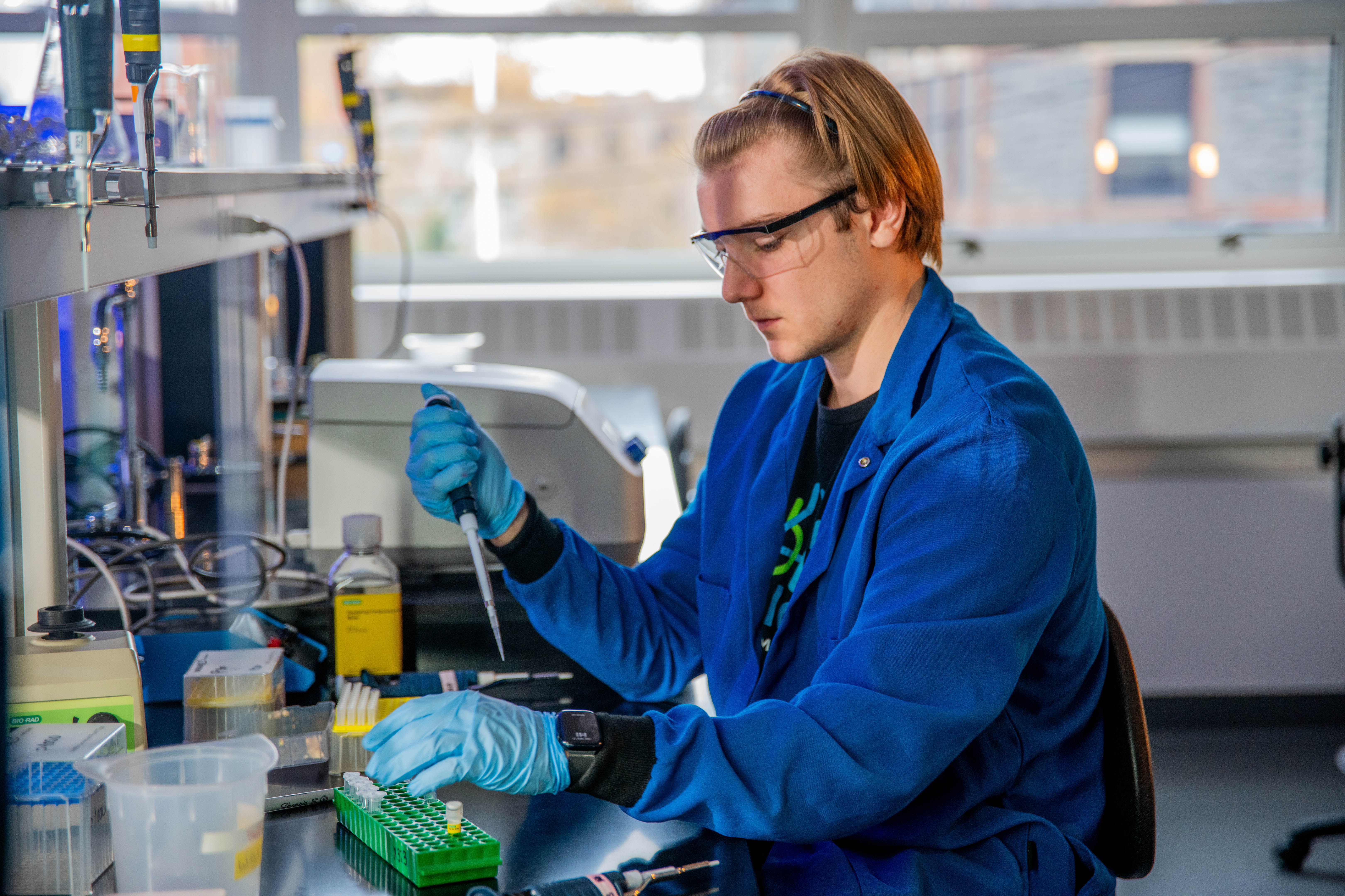 A young male students uses a pipette and vial to conduct research