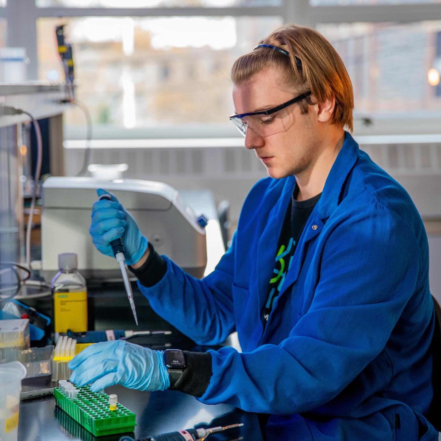 A young male students uses a pipette and vial to conduct research