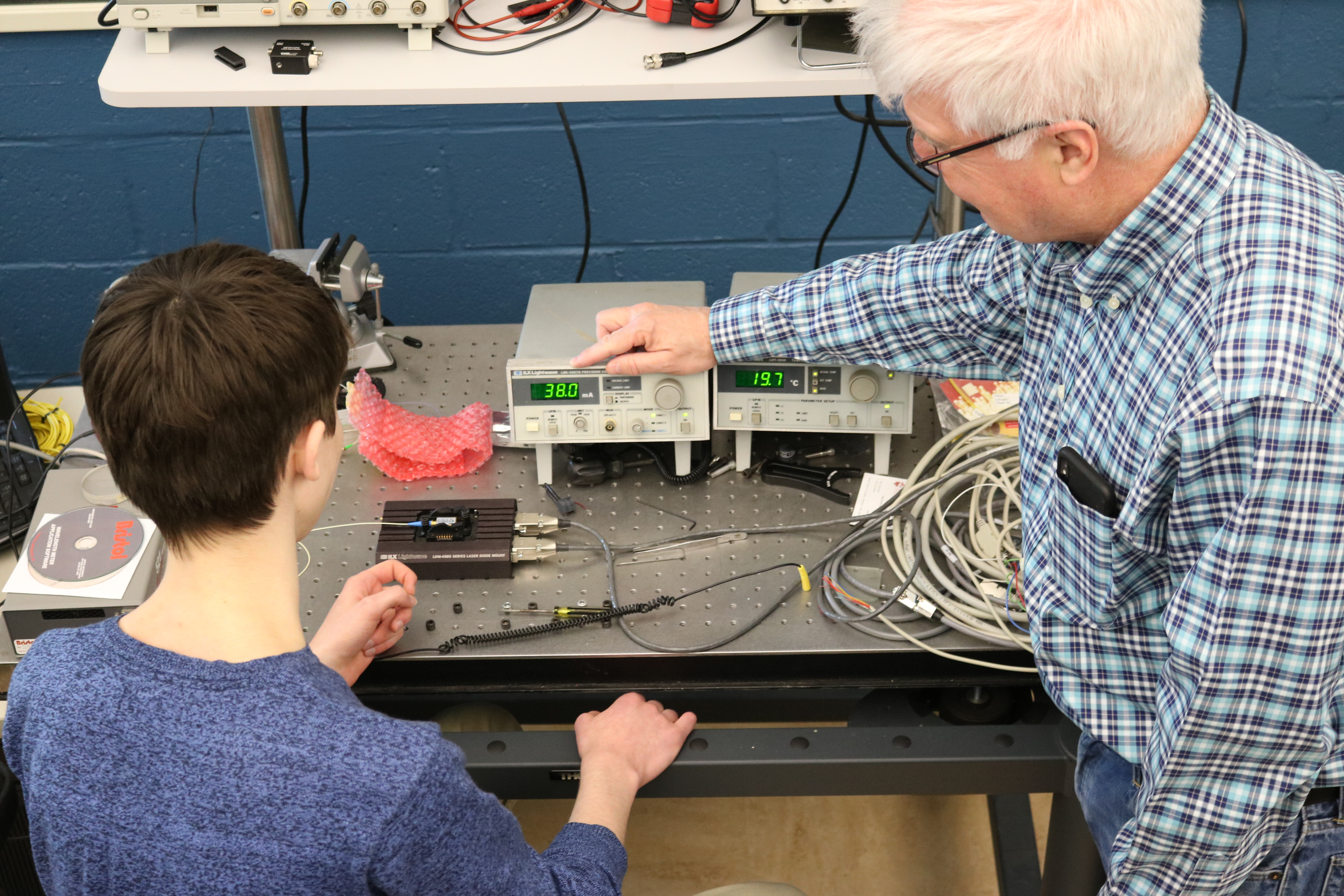A student and faculty member working with equipment inside of a Physics lab.