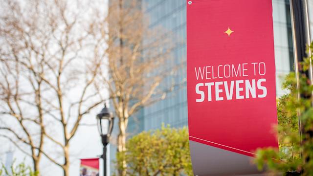 Red Welcome to Stevens banner on lamp post on campus