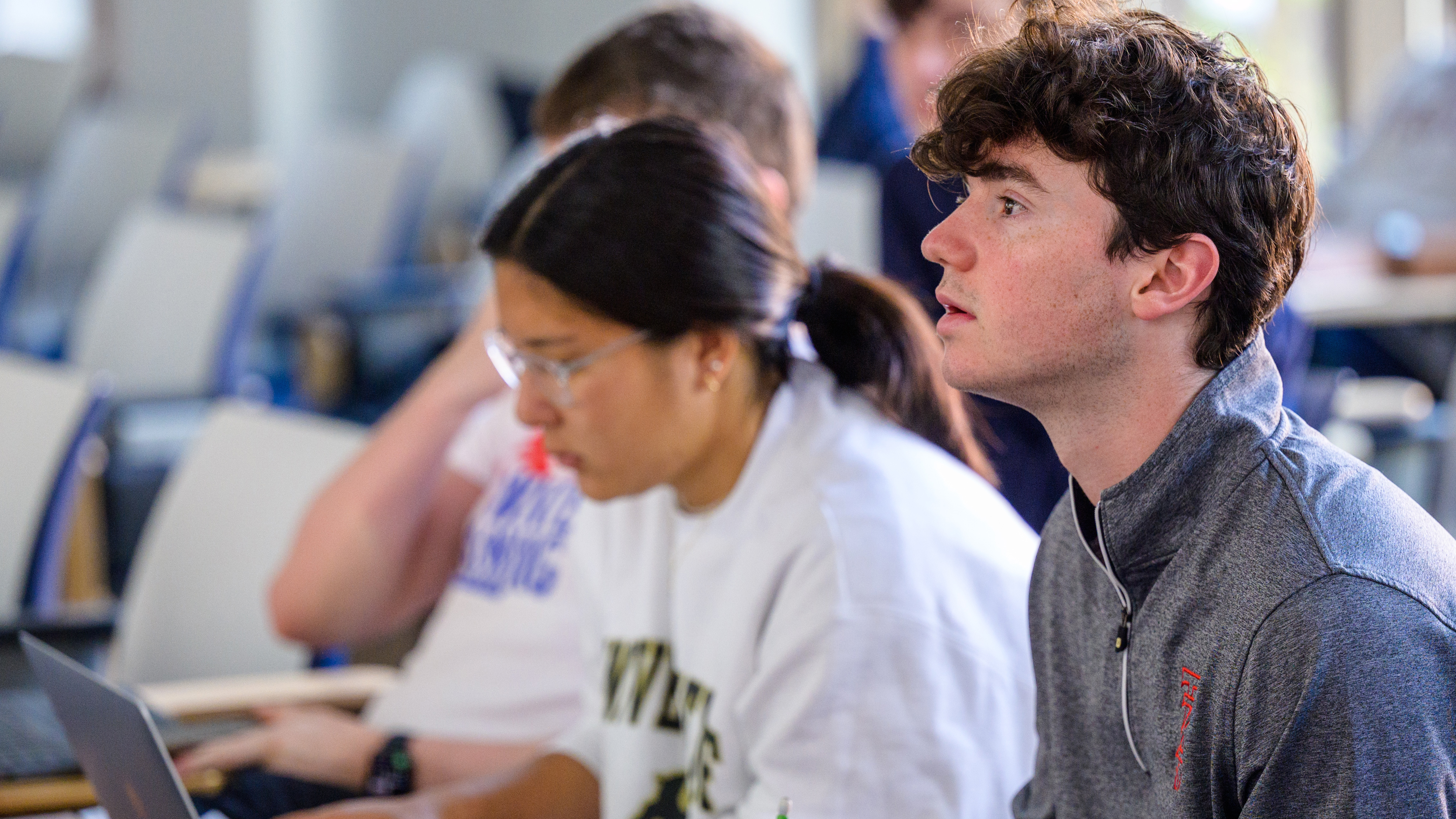 Two students in class taking notes during a lecture.