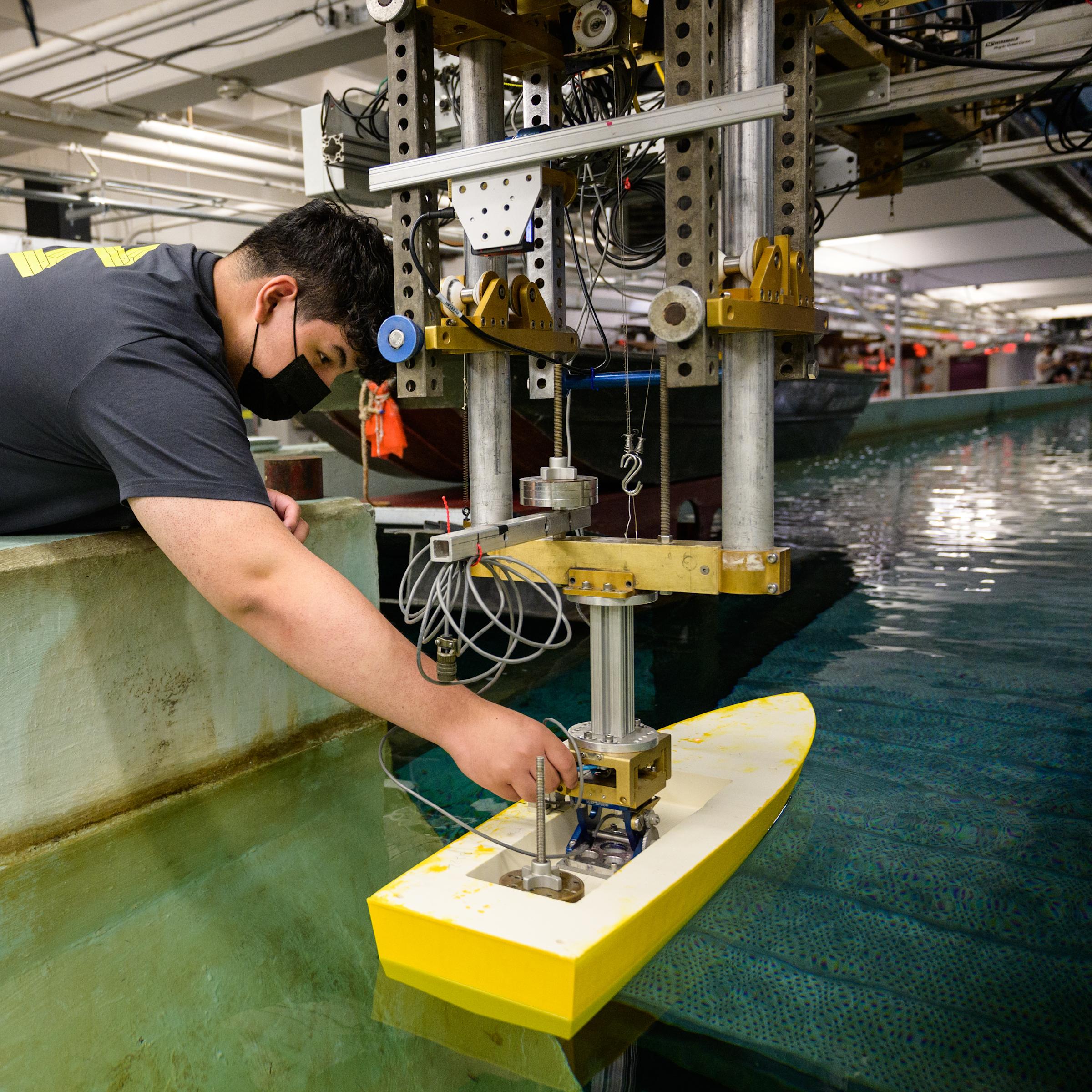 student testing a boat model in Davidson Lab wave tank