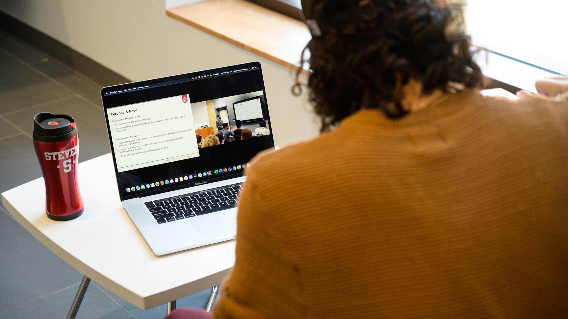 A student watches a lecture on his laptop.