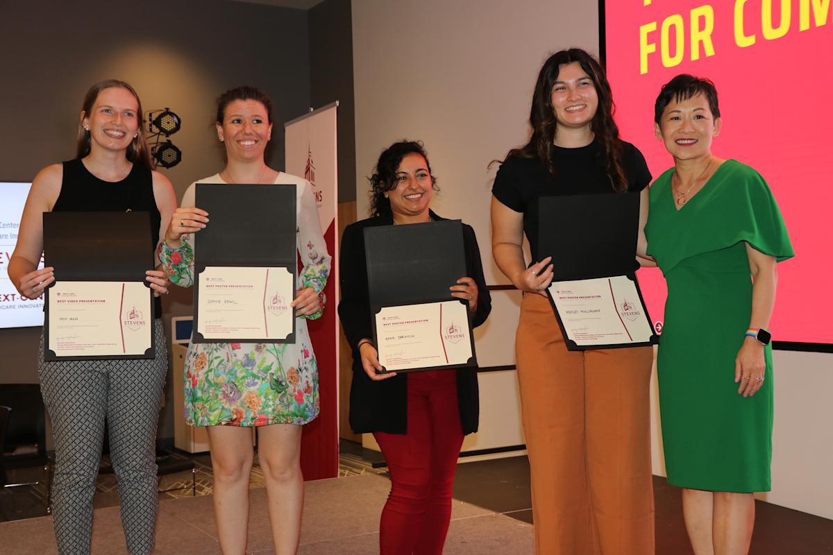 Jennifer Kang-Mieler stands on the right side of four women holding award certificates in front of themselves, posing for a photo and smiling at the camera.
