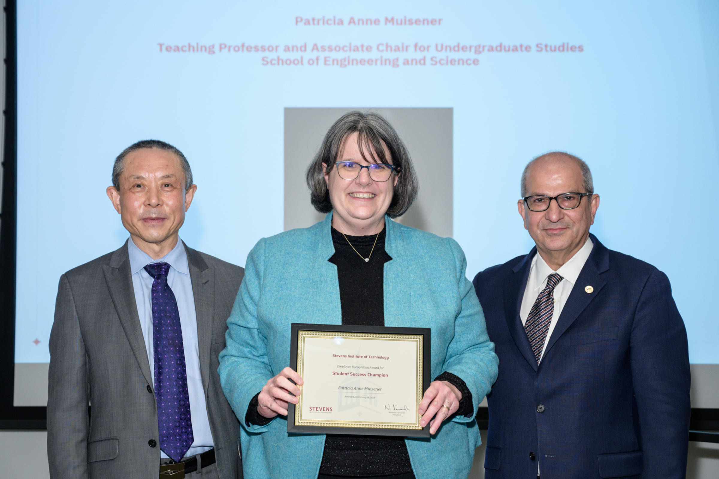 Patricia Muisener and David Zeng stand next to each other holding an award. The shot is from the waist up.