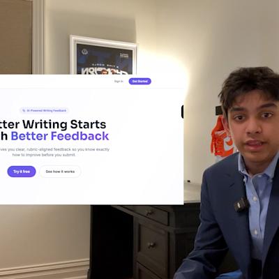 A young professional in a navy blazer and light blue shirt presents during a video call, with the GradeLift website visible on screen showing their AI-powered writing feedback platform.