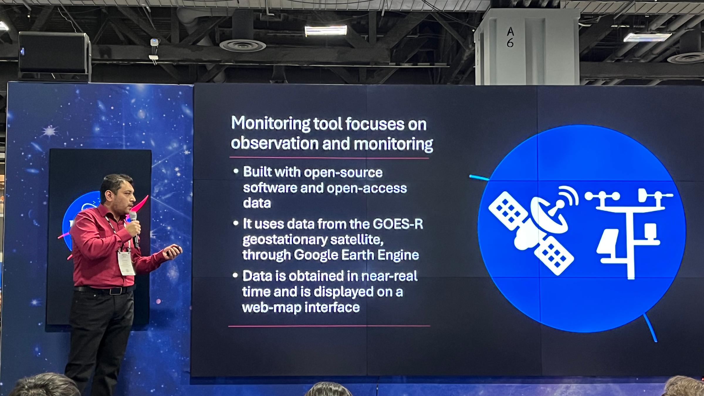 Jorge Bravo, a Stevens Ph.D. student, standing on stage presenting to an audience a slide about weather observation and monitoring.