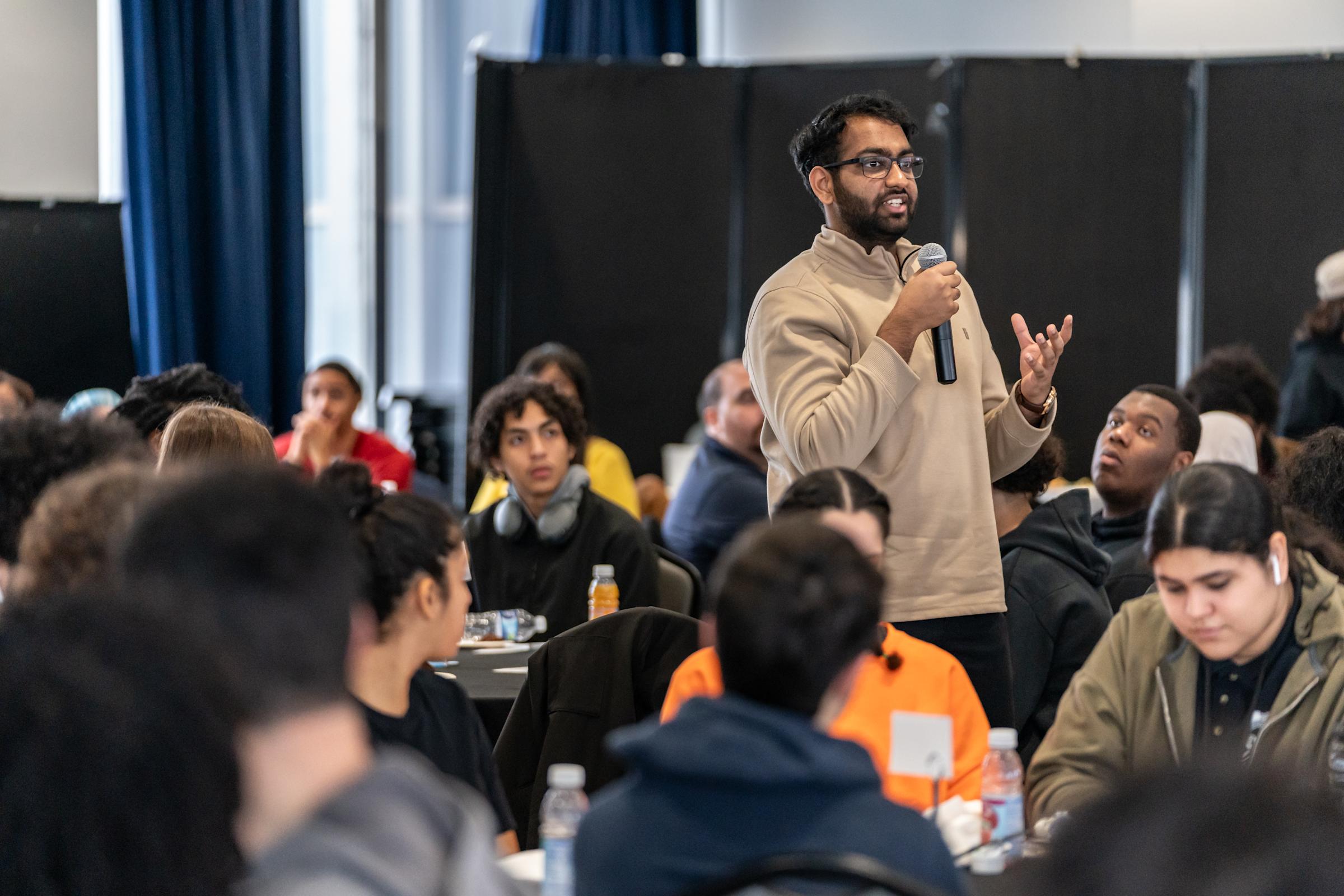 A participant in the Junior Achievement workshop asks a question while holding a microphone.
