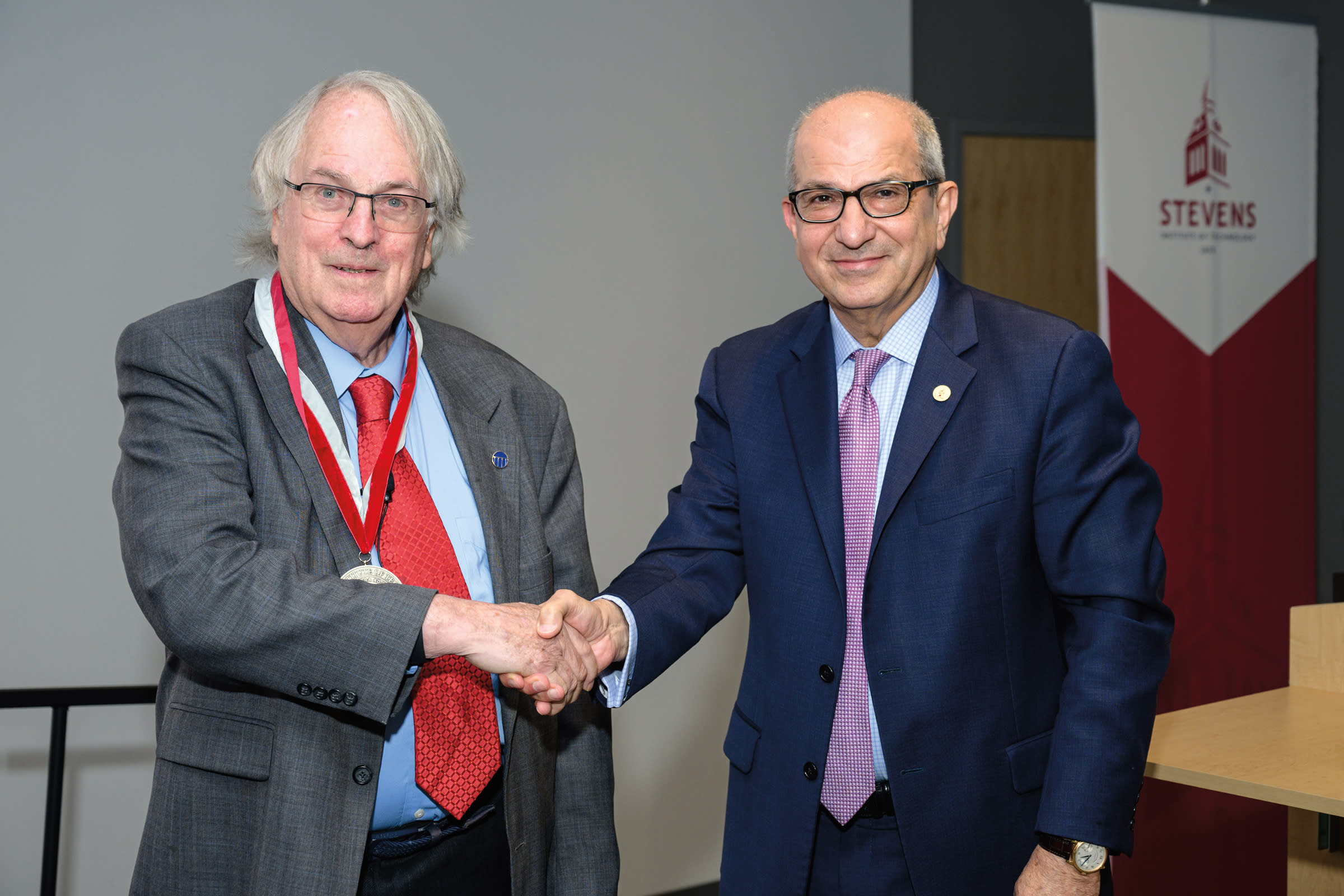 Photo of M. Stanley Whittingham, left, shaking hands with Stevens President Nariman Farvardin.
