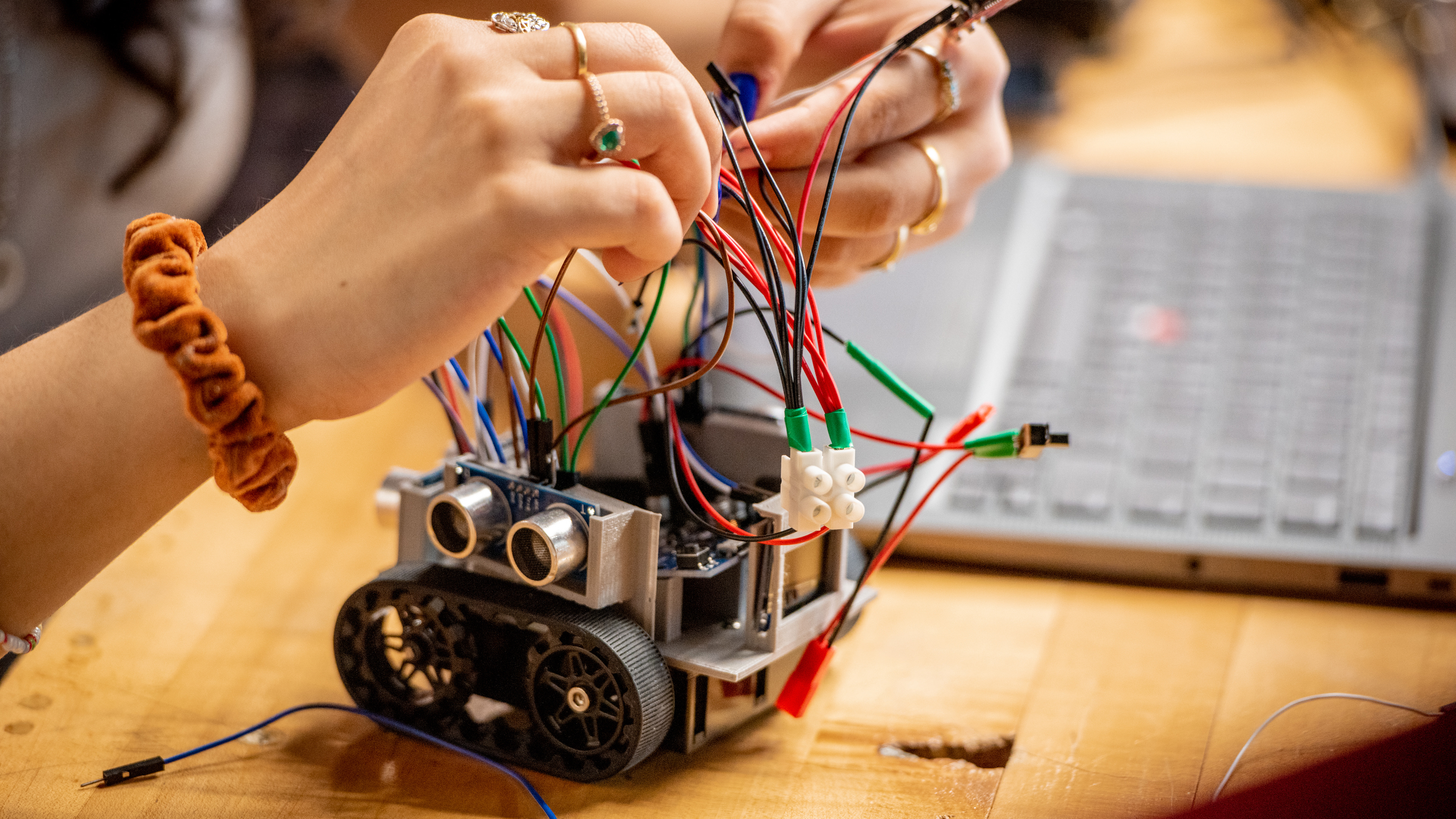 Close-up of hands working on a small robot.