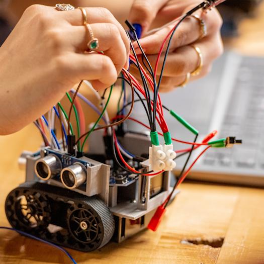 Close-up of hands working on a small robot.