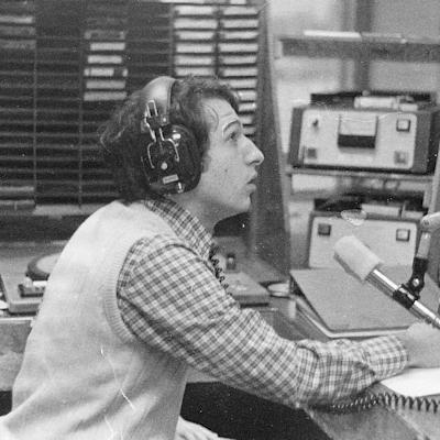Black and white photo featuring Paul Porzio ’77 speaking into a radio microphone while seated and wearing headphones at WCPR at Stevens in 1975