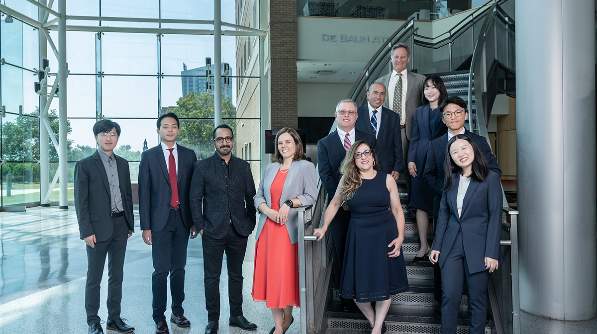 Group photo of 11 new faculty members in the atrium of the Babbio Center.