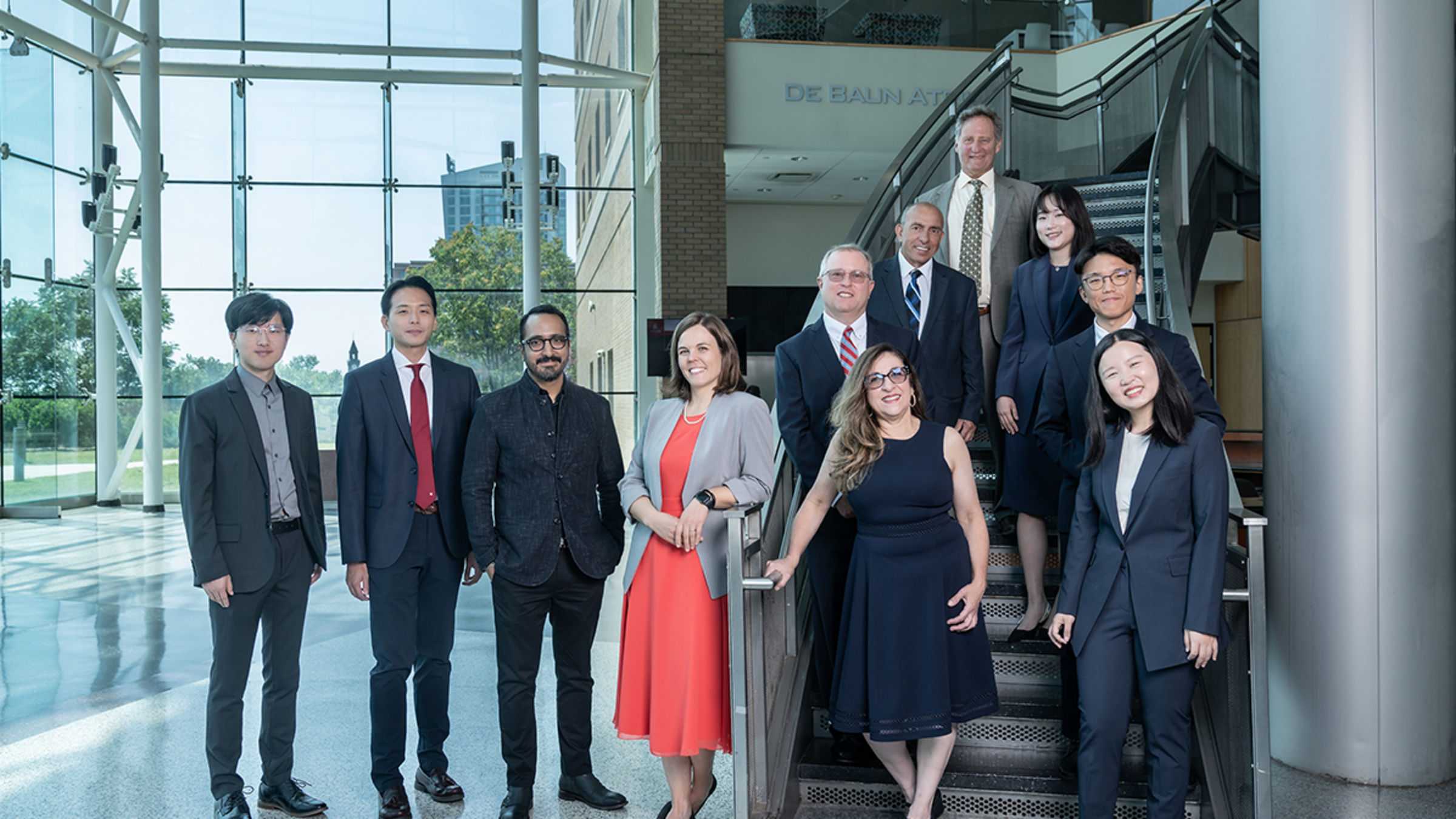 Group photo of 11 new faculty members in the atrium of the Babbio Center.