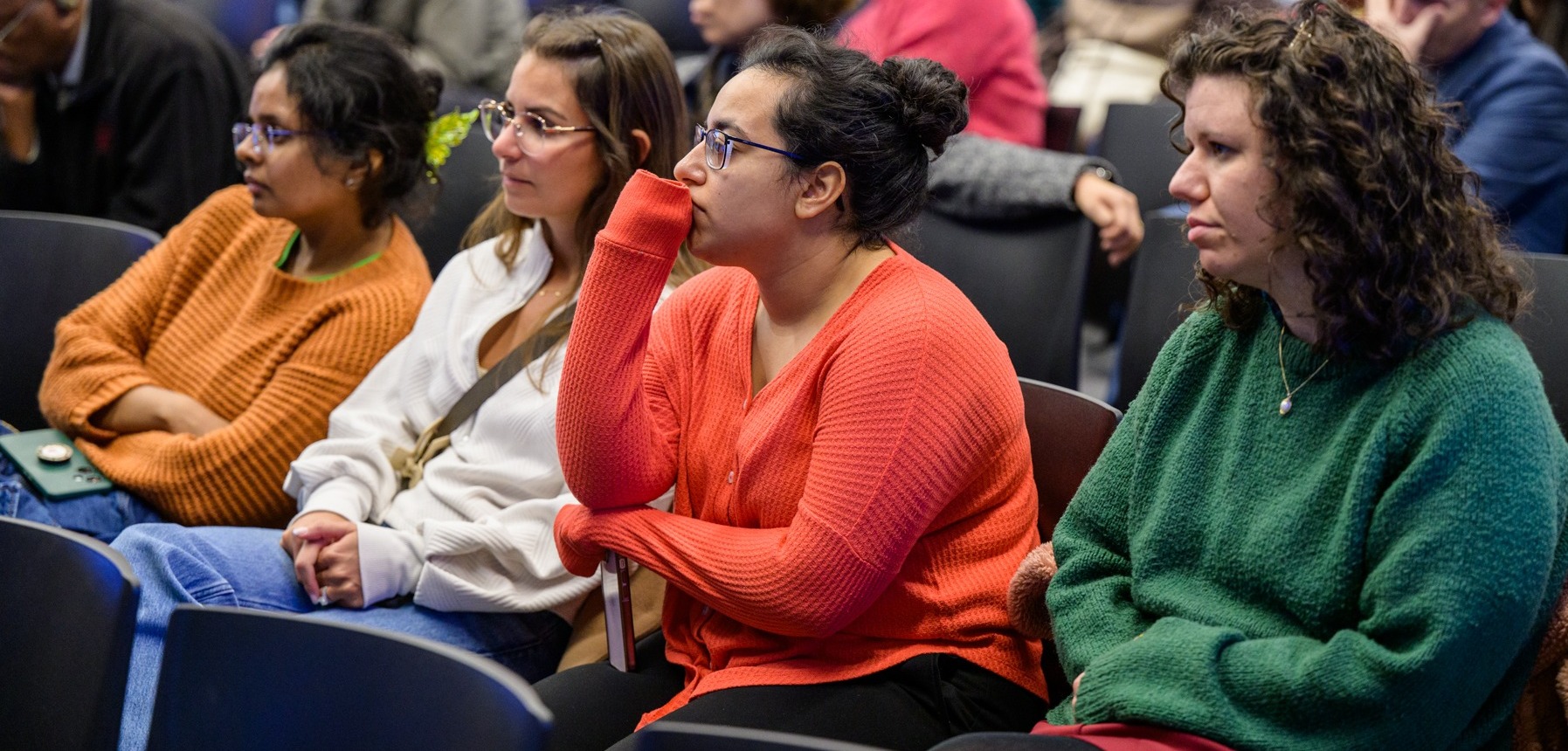 Audience seated in rows, attending the CHI Relaunch event, with several individuals wearing colorful sweaters.