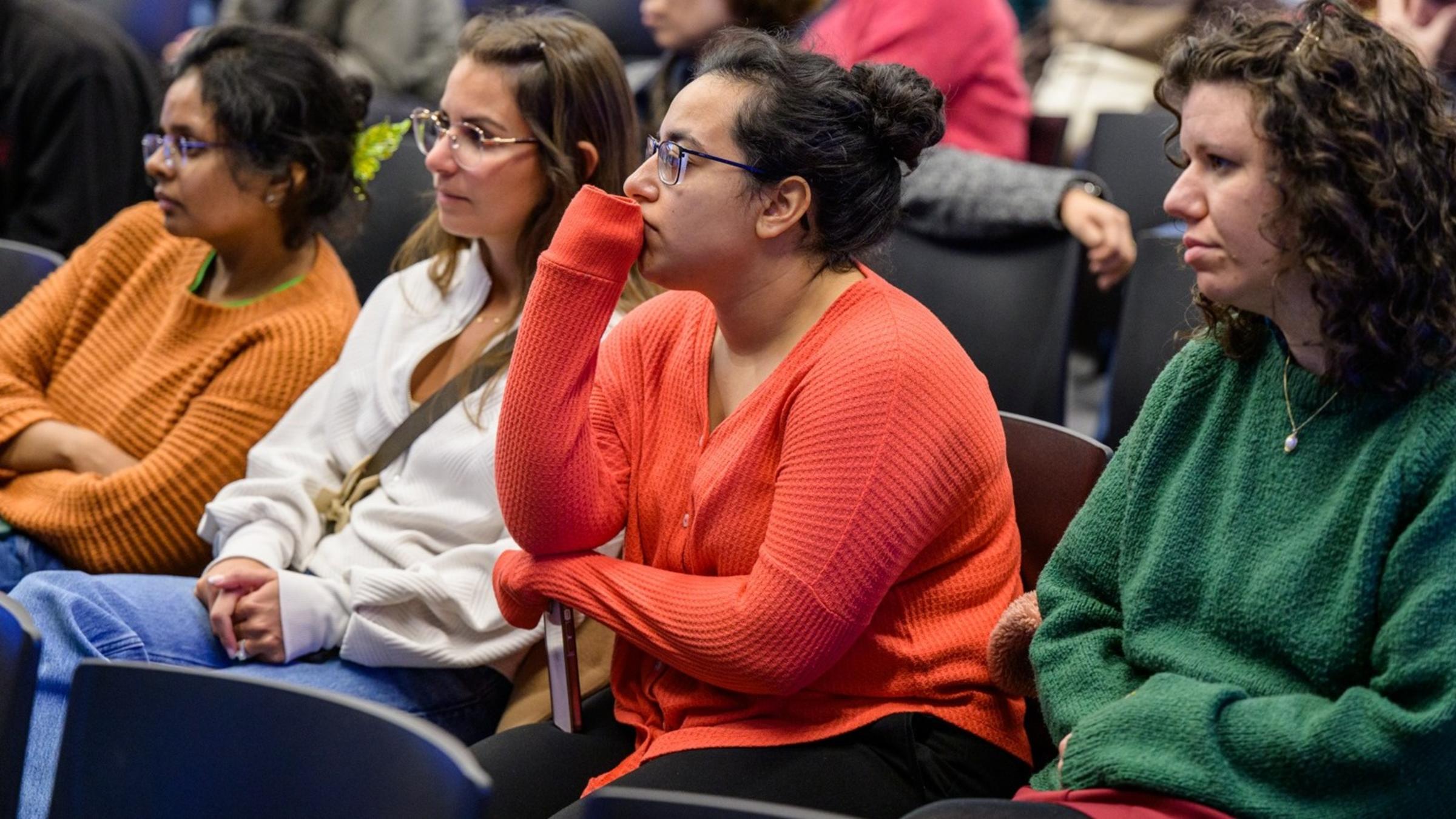 Audience seated in rows, attending the CHI Relaunch event, with several individuals wearing colorful sweaters.
