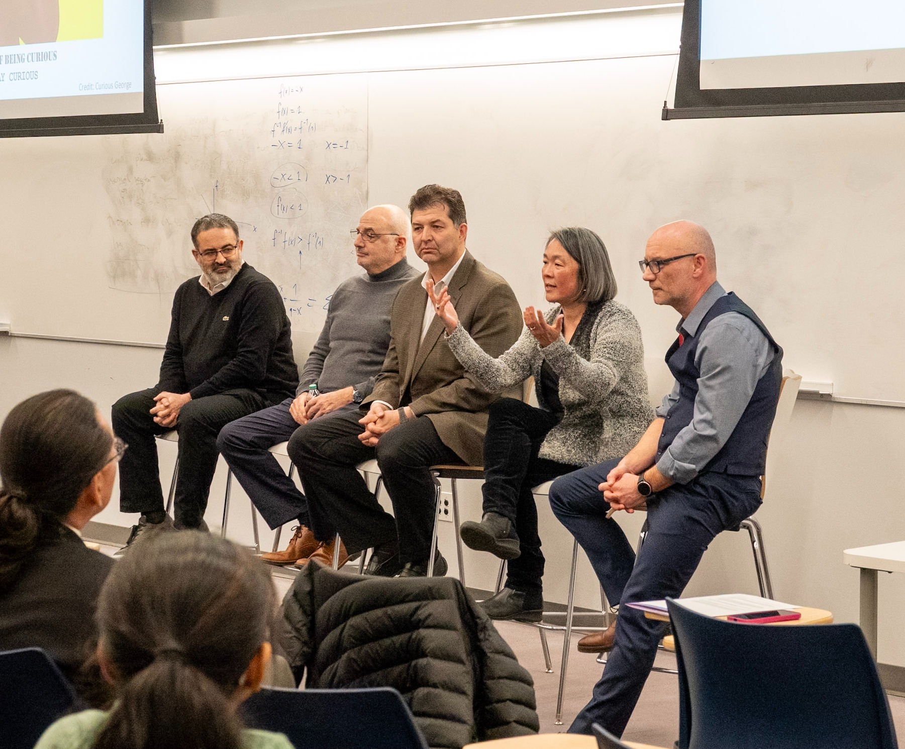 Industry and academic guest speakers sit at a seminar with professor Marcin Iwanicki.