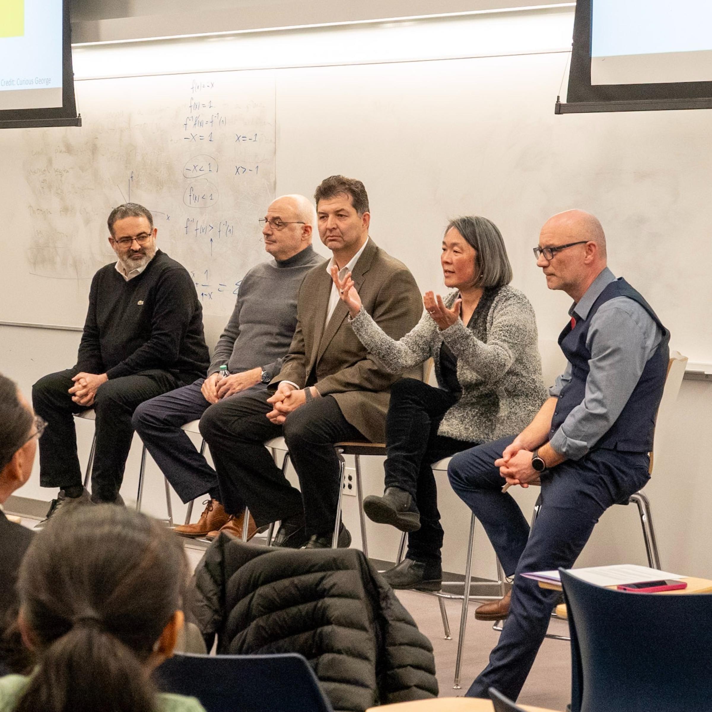 Industry and academic guest speakers sit at a seminar with professor Marcin Iwanicki.