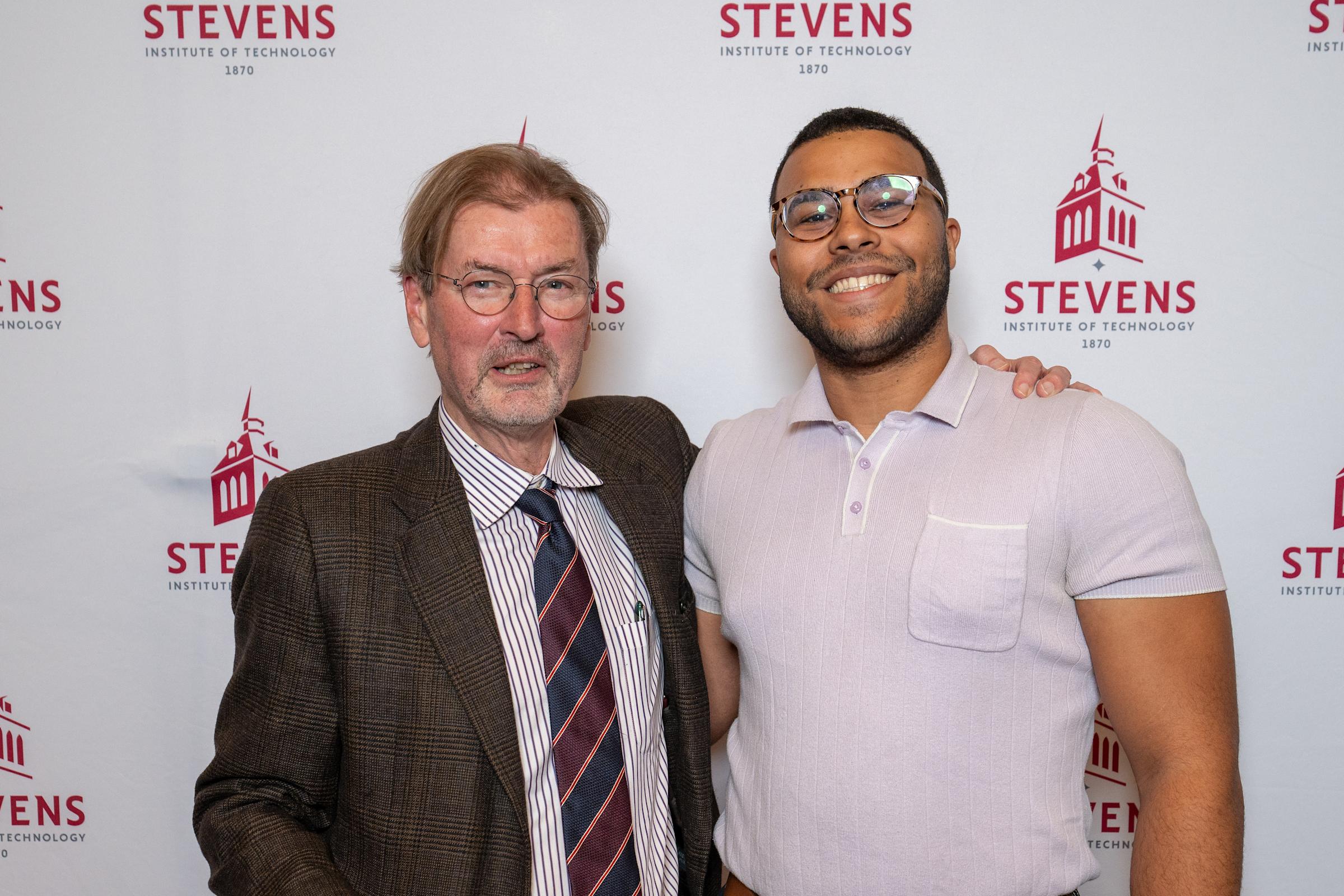 George Calhoun and an alum pose in front of a Stevens step-and-repeat