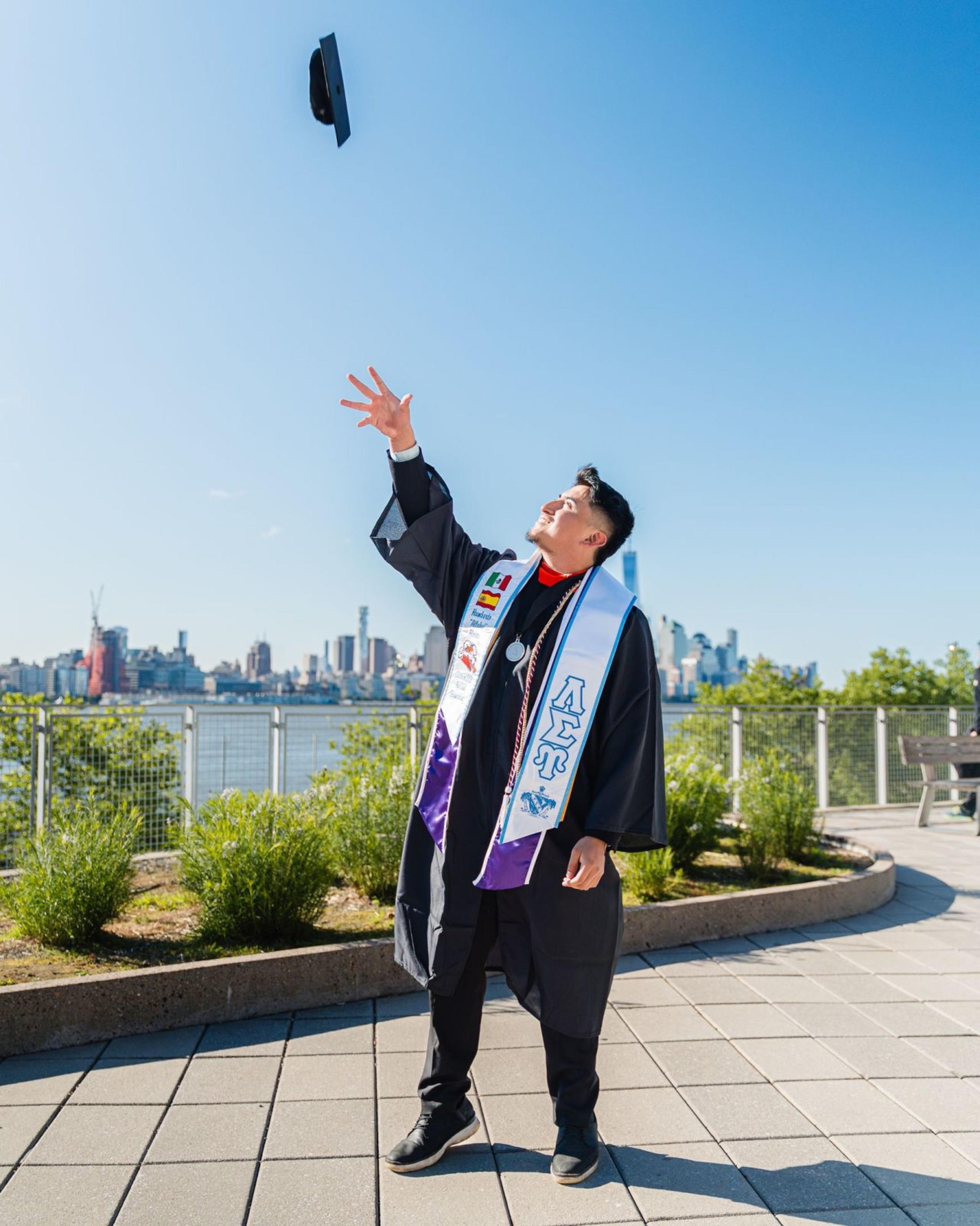 Humberto Flores ’25 tosses his graduation cap at the Babbio patio