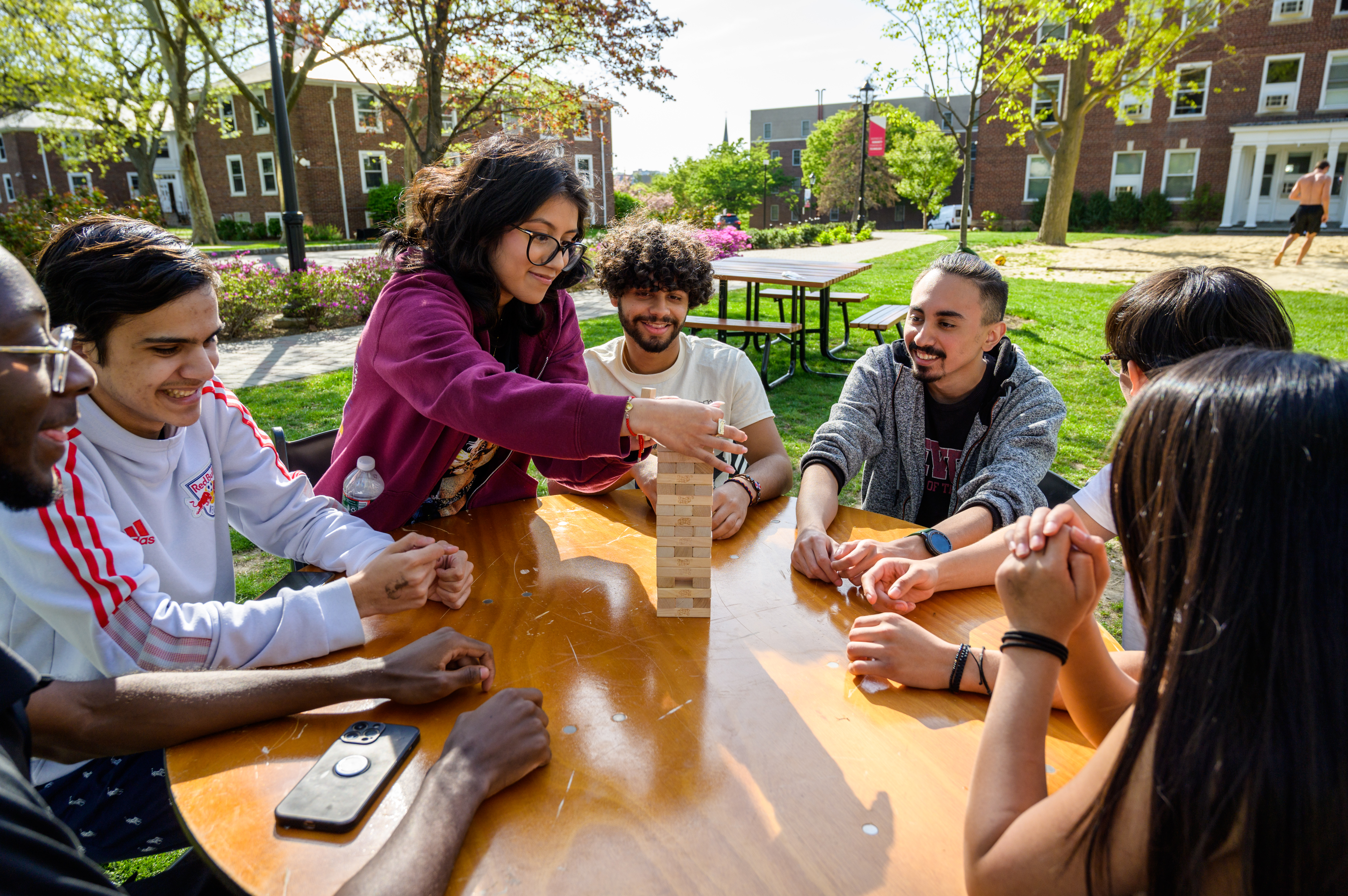 Students gather outside to play Jenga on a table on campus