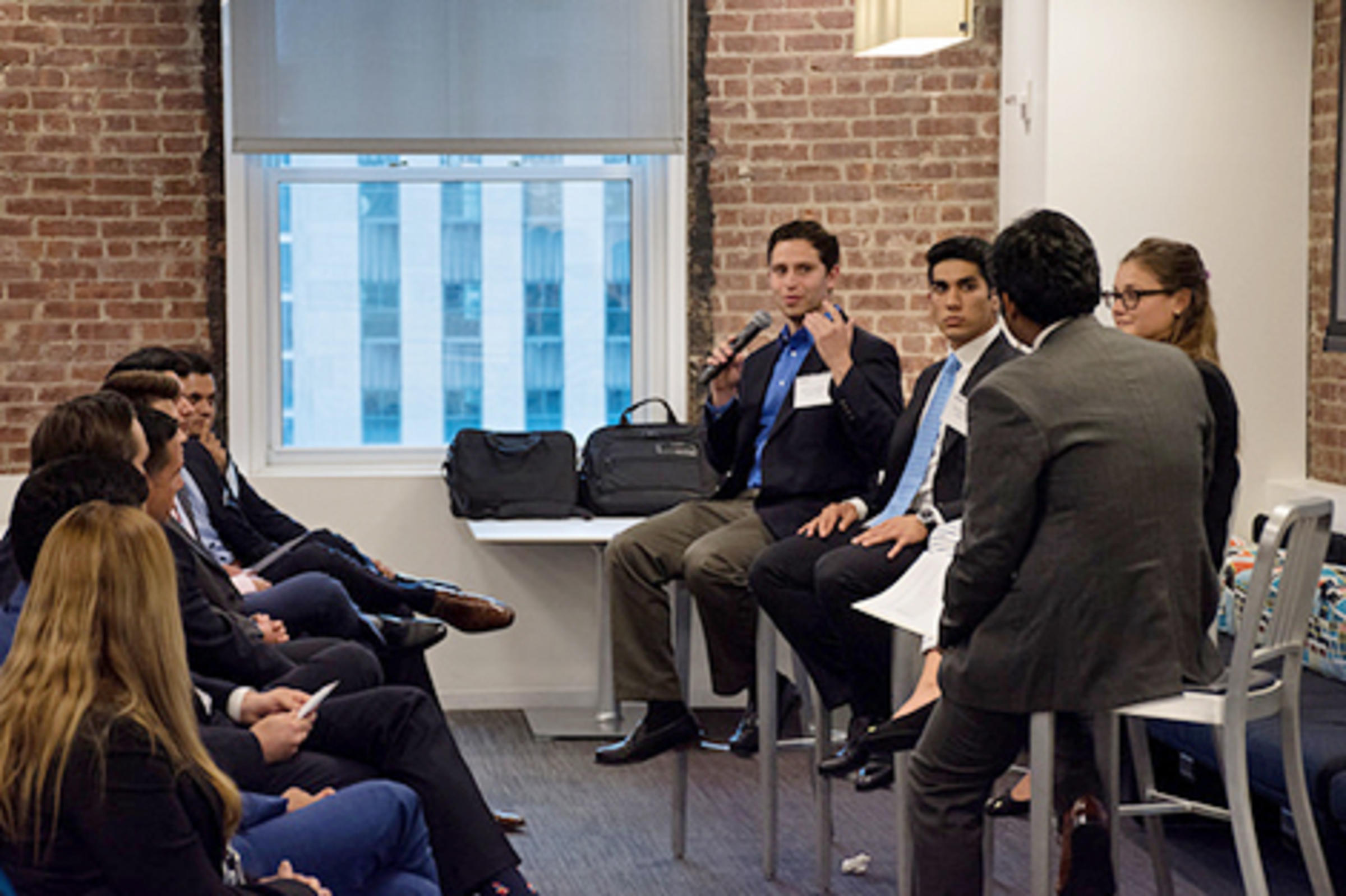 Seth Kirschner holds a microphone and speaks during a meeting in Deloitte's offices.