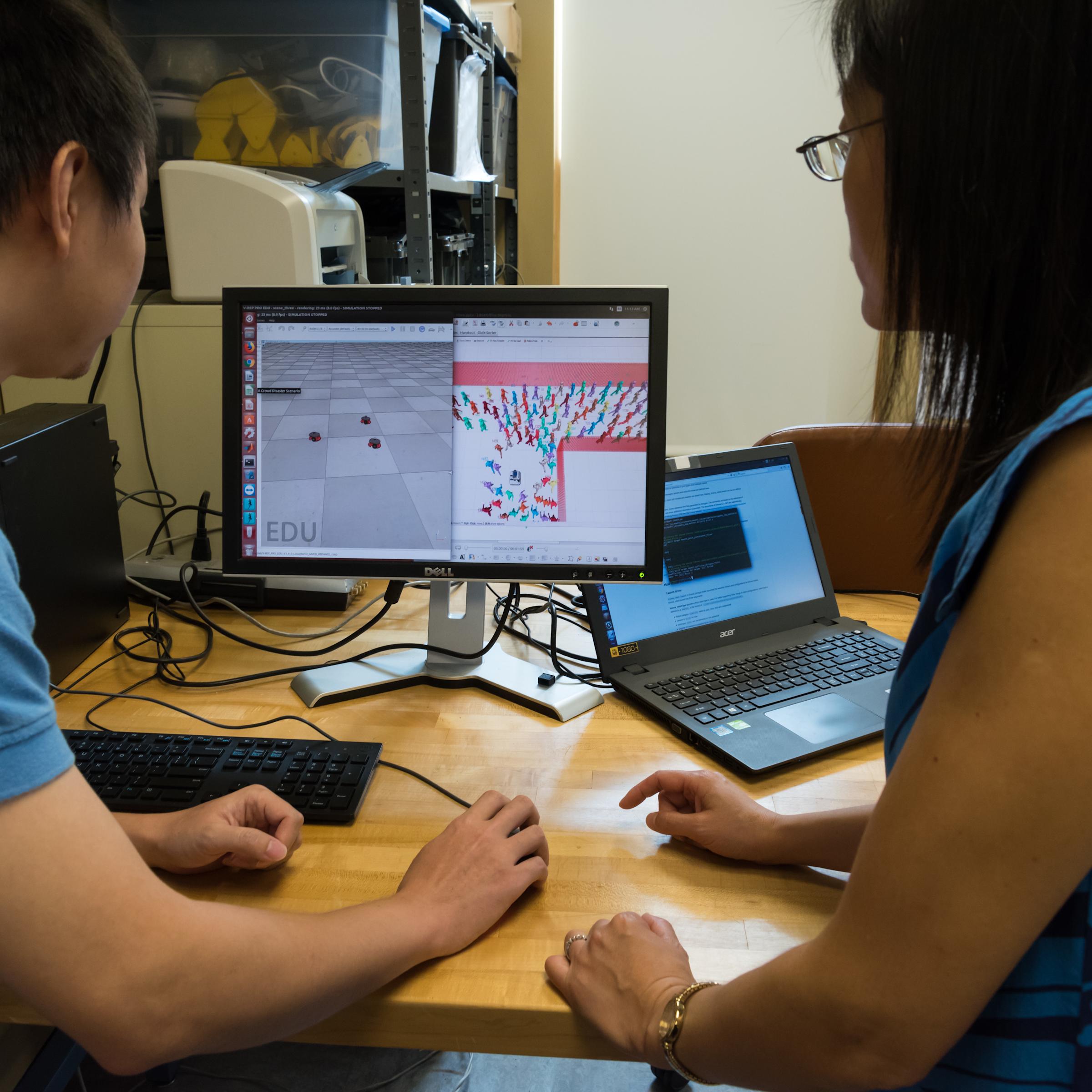 Yi Guo and student looking at a computer