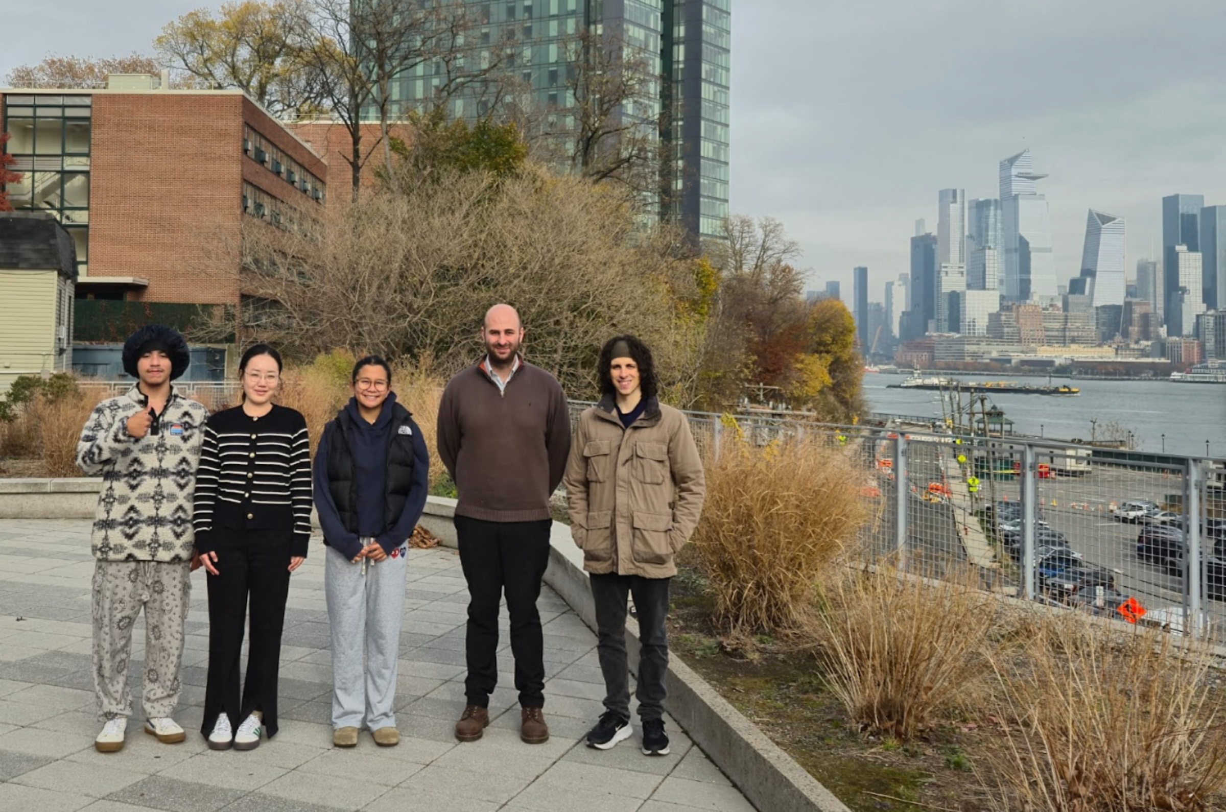 Simon Mahler posing with his lab group on Stevens campus in front of the New York City skyline.