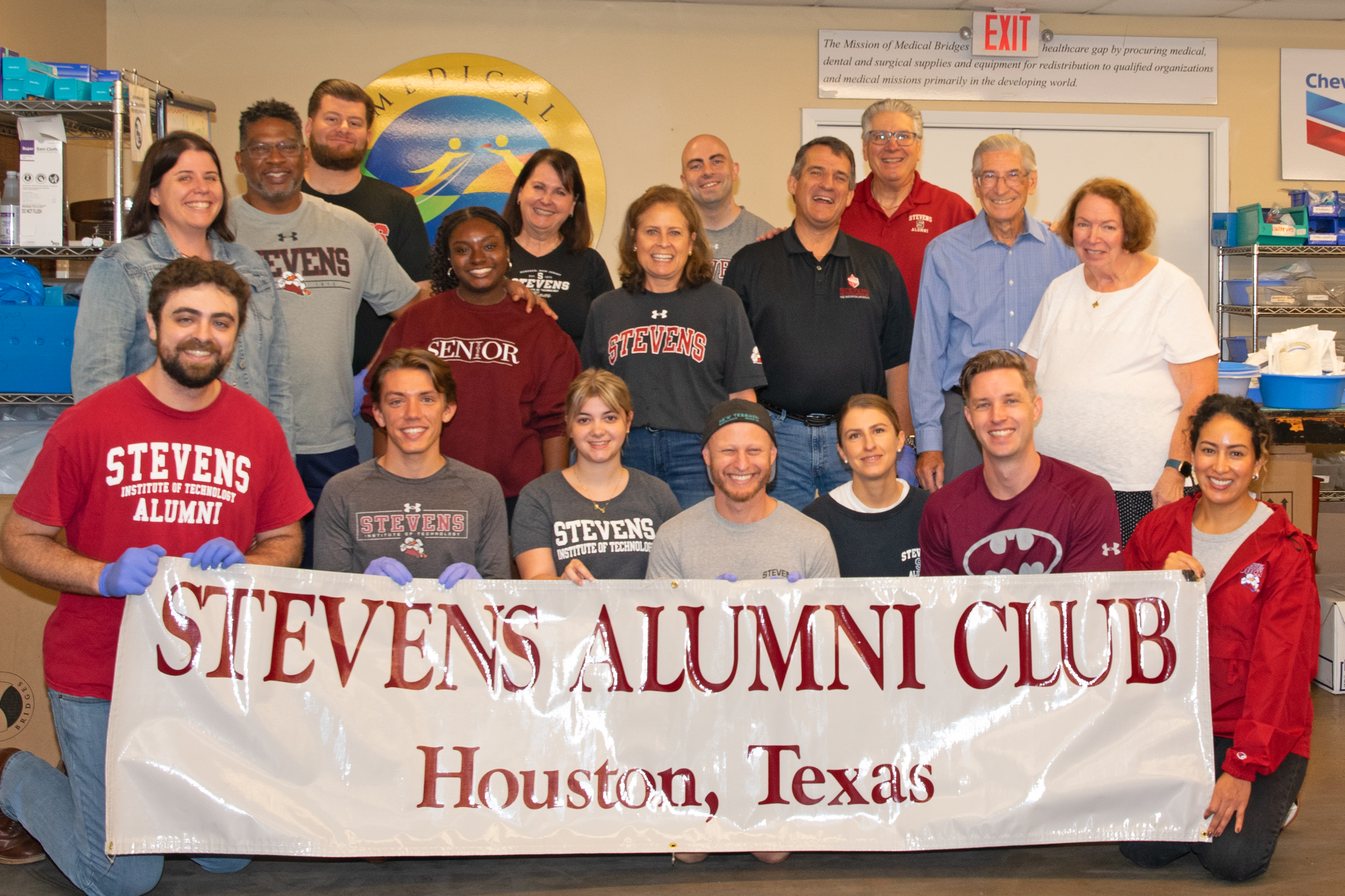 Stevens Houston Alumni Network gather for the annual service day at Medical Bridges in 2025, posing for a group photo with the Alumni Club banner