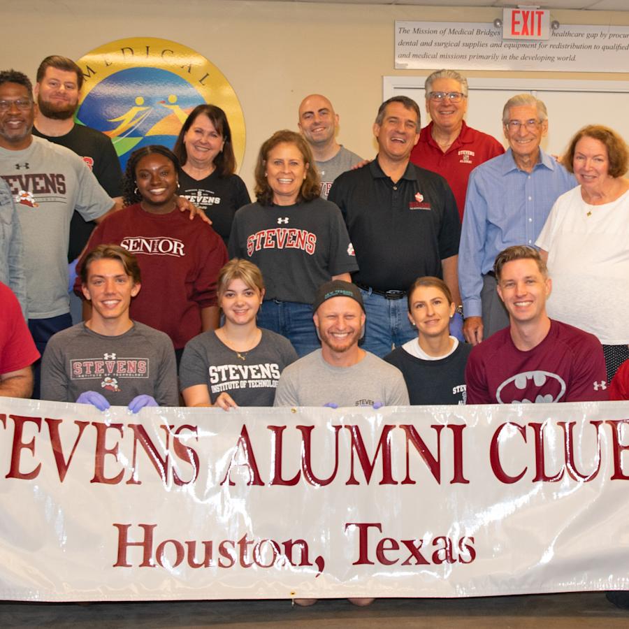 Stevens Houston Alumni Network gather for the annual service day at Medical Bridges in 2025, posing for a group photo with the Alumni Club banner
