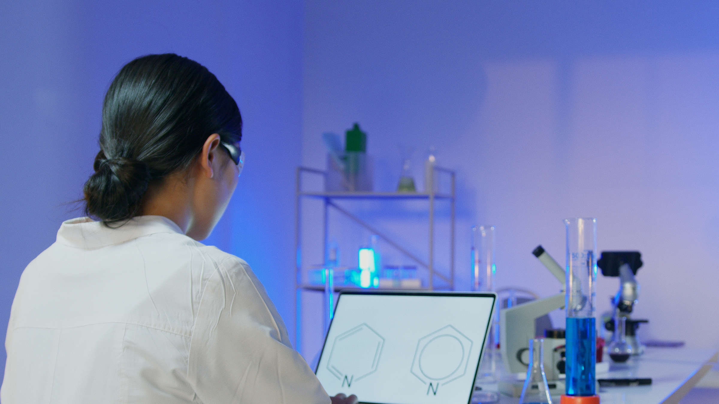 Scientist working at computer with a chemical formula on the screen