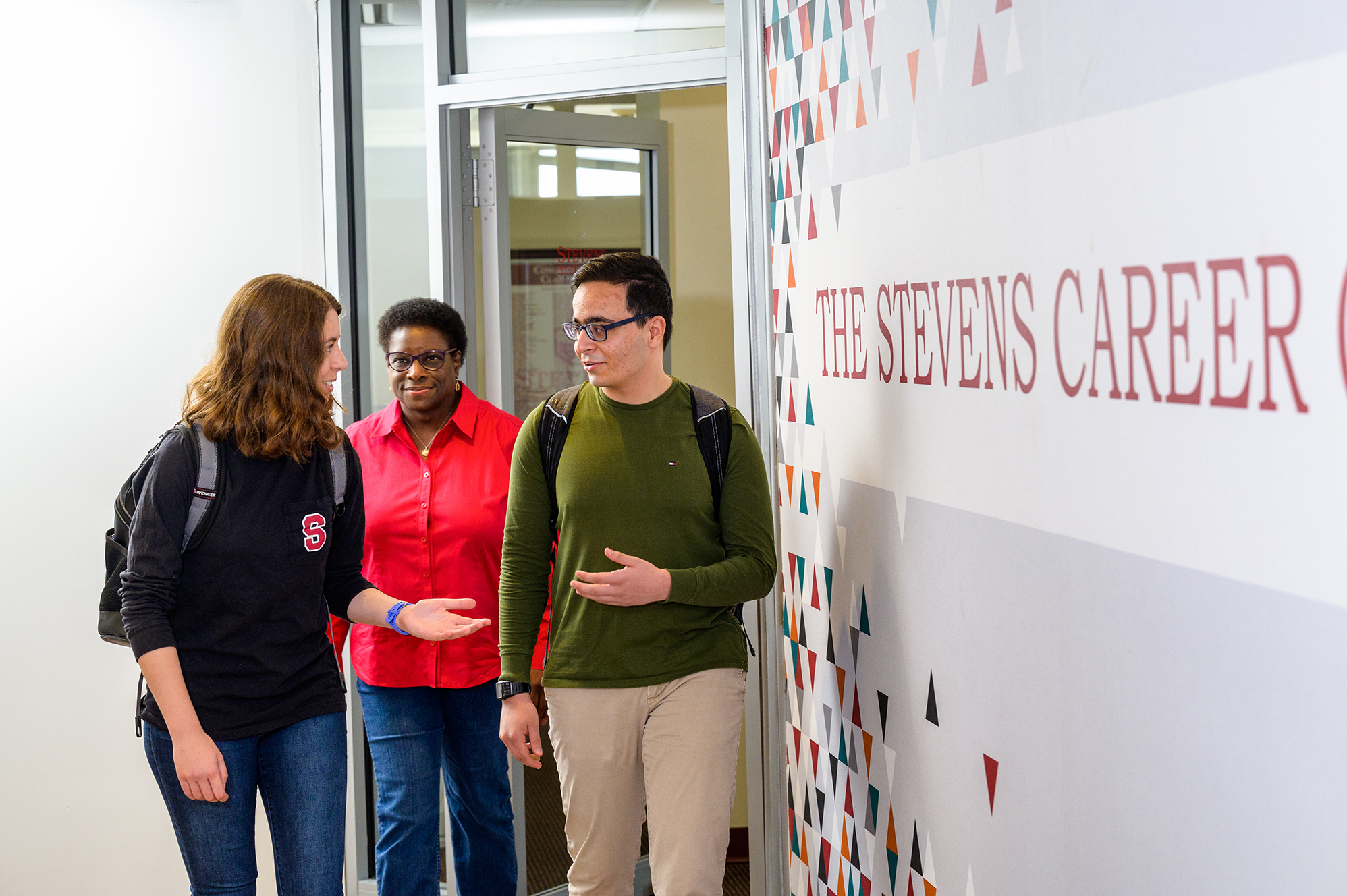 Counselor and two students walking next to Career Service sign