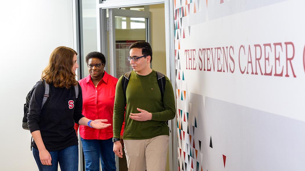 Counselor and two students walking next to Career Service sign