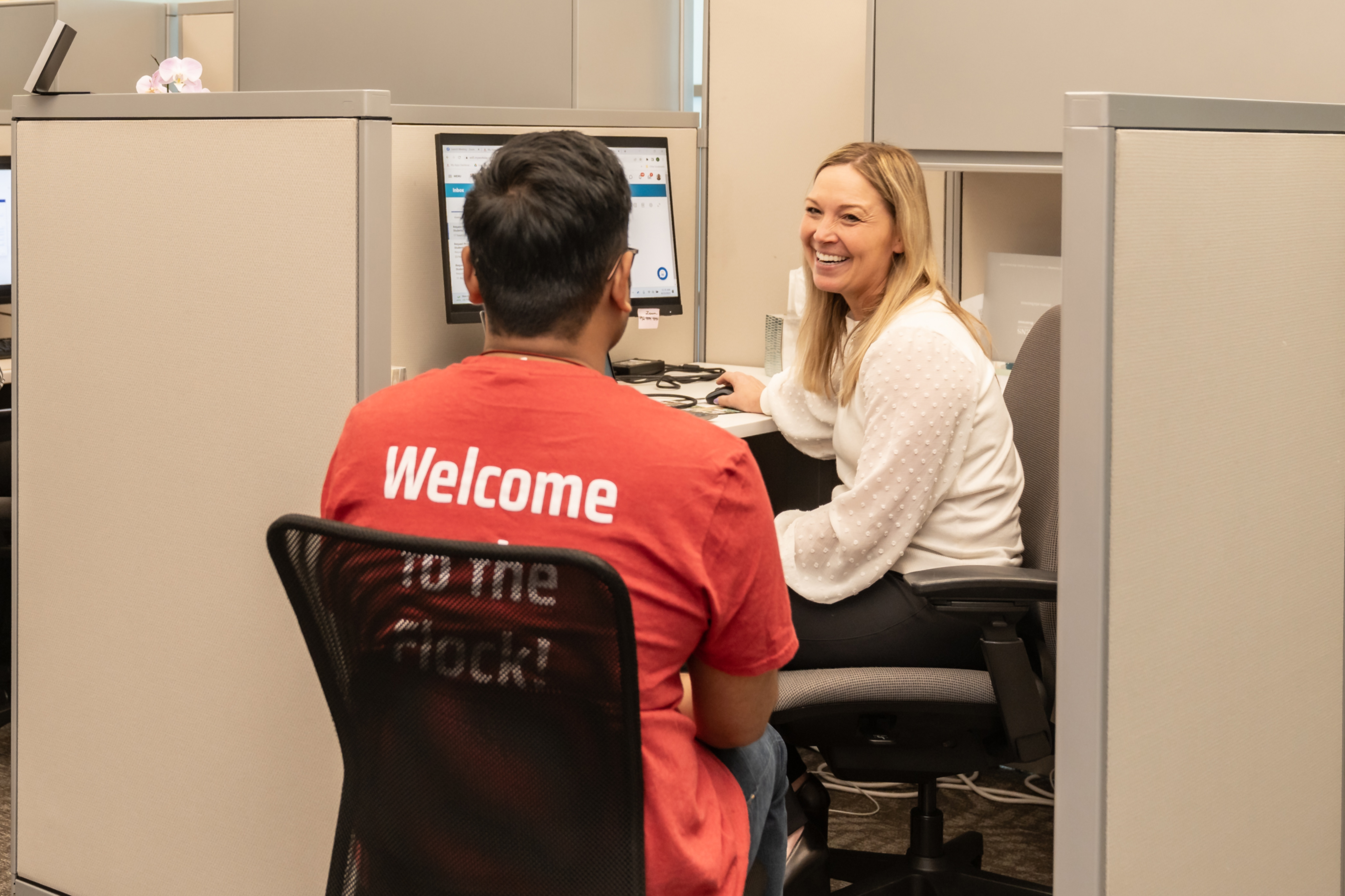 A smiling Success advisors works with a student at their desk.