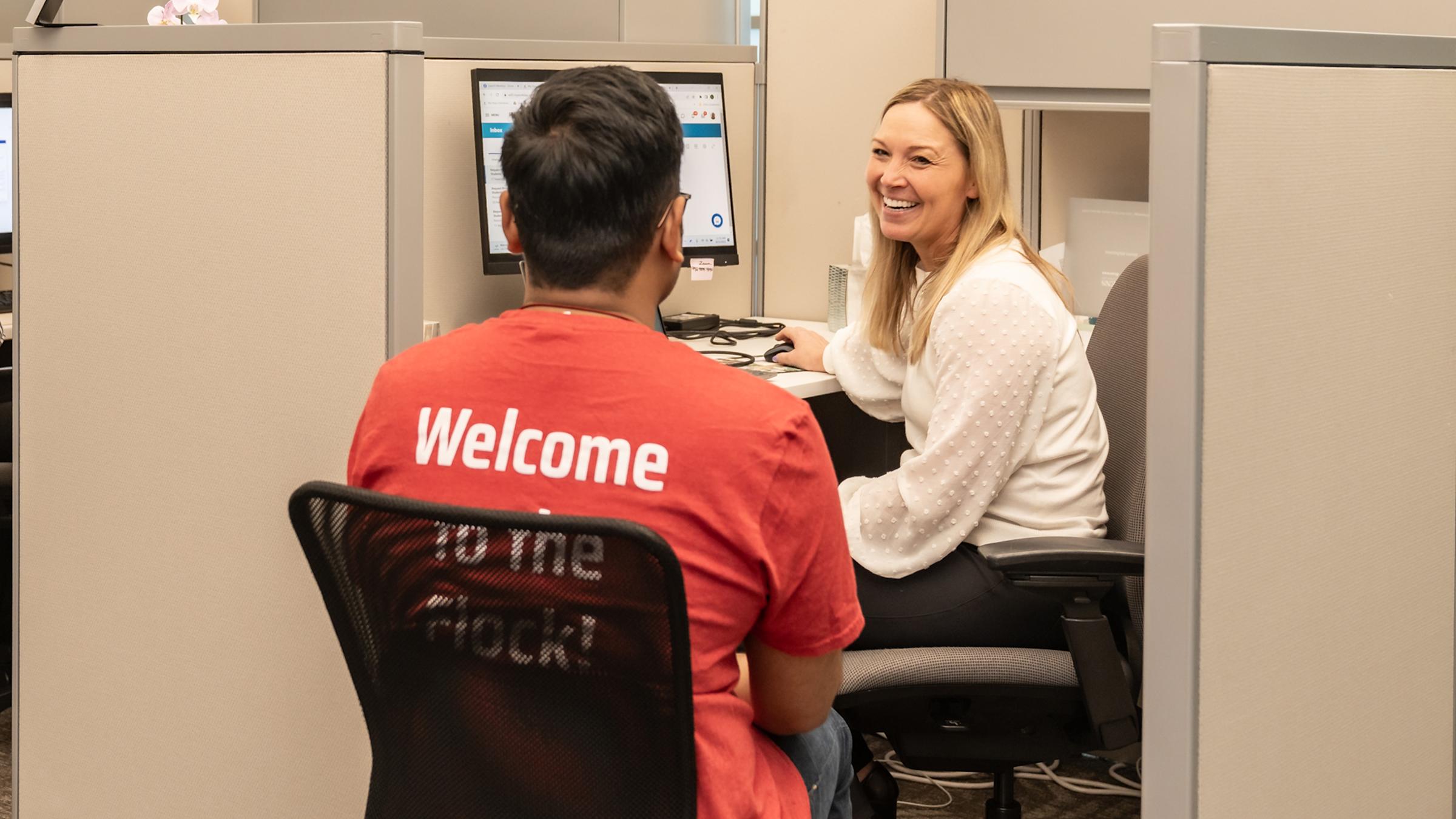 A smiling Success advisors works with a student at their desk.