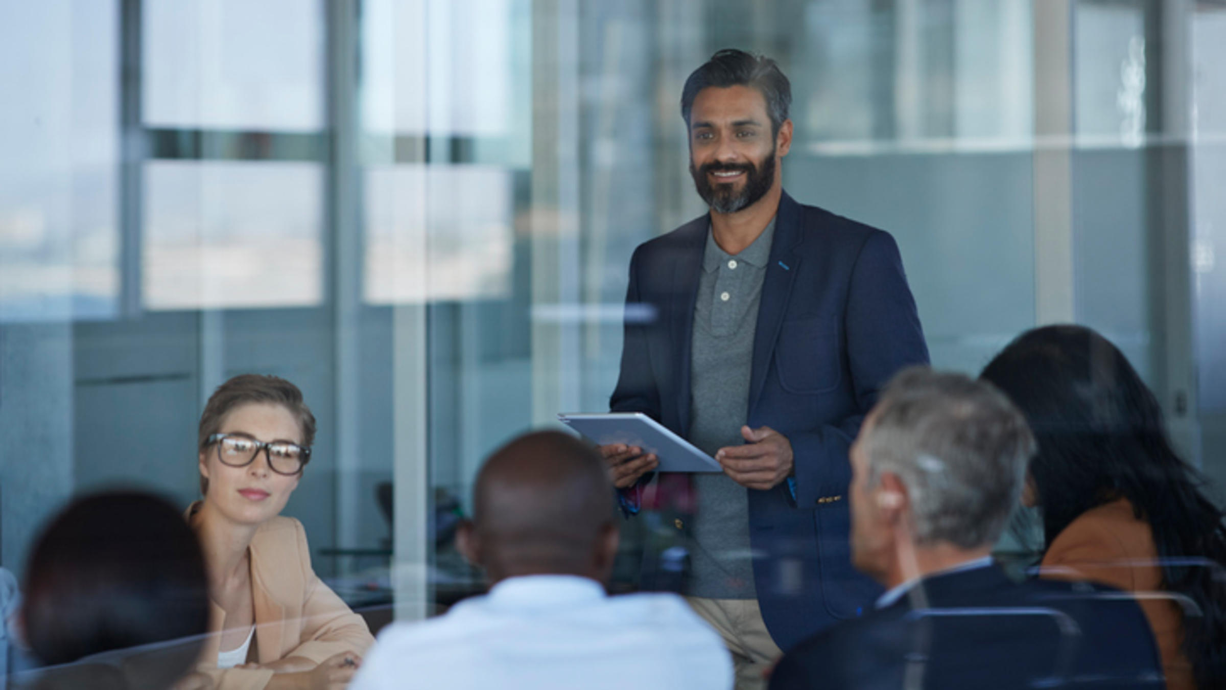 one man standing with sitting colleagues in conference room