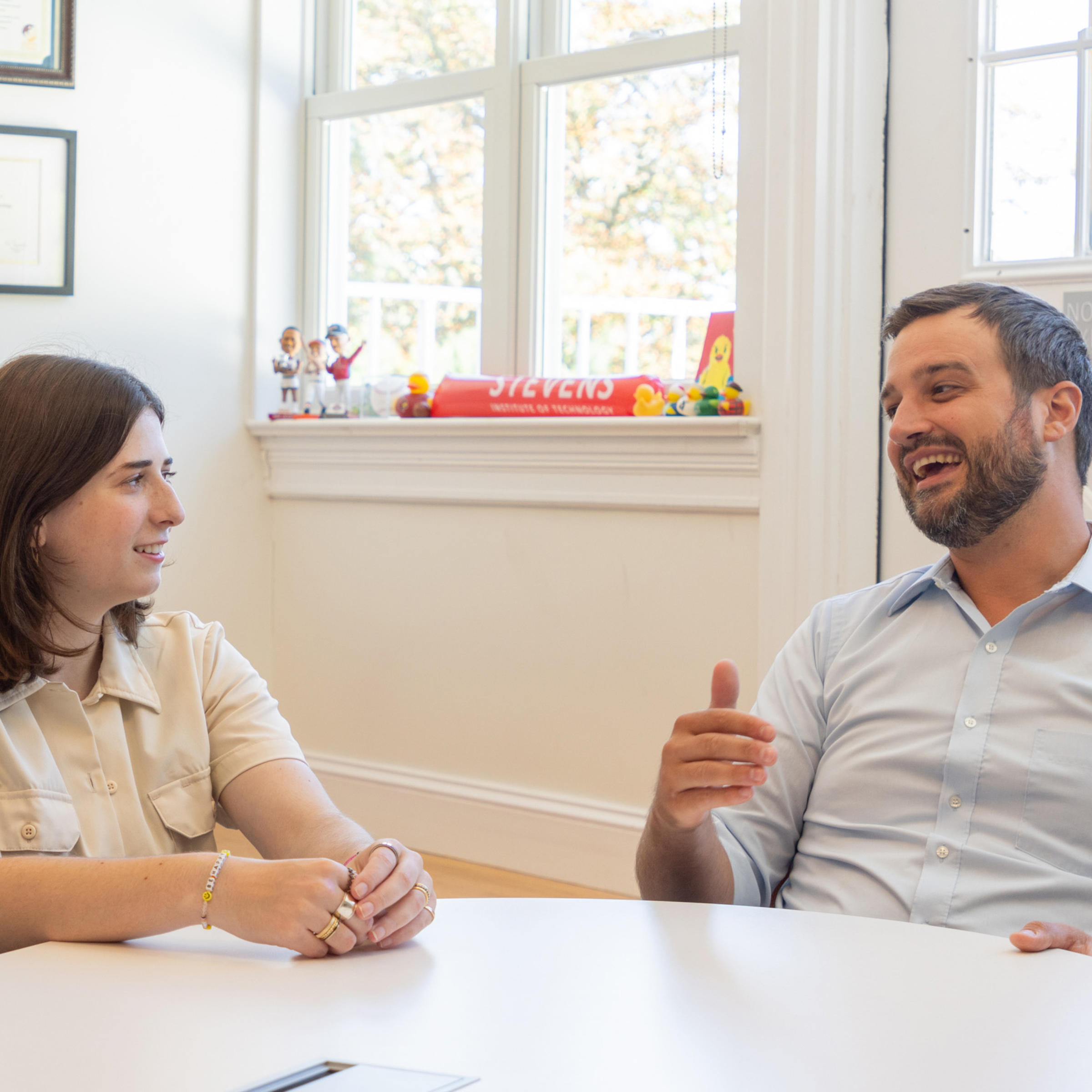 Lily Stone and Phillip Gehman talking at a table in Gehman’s office on a sunny day.